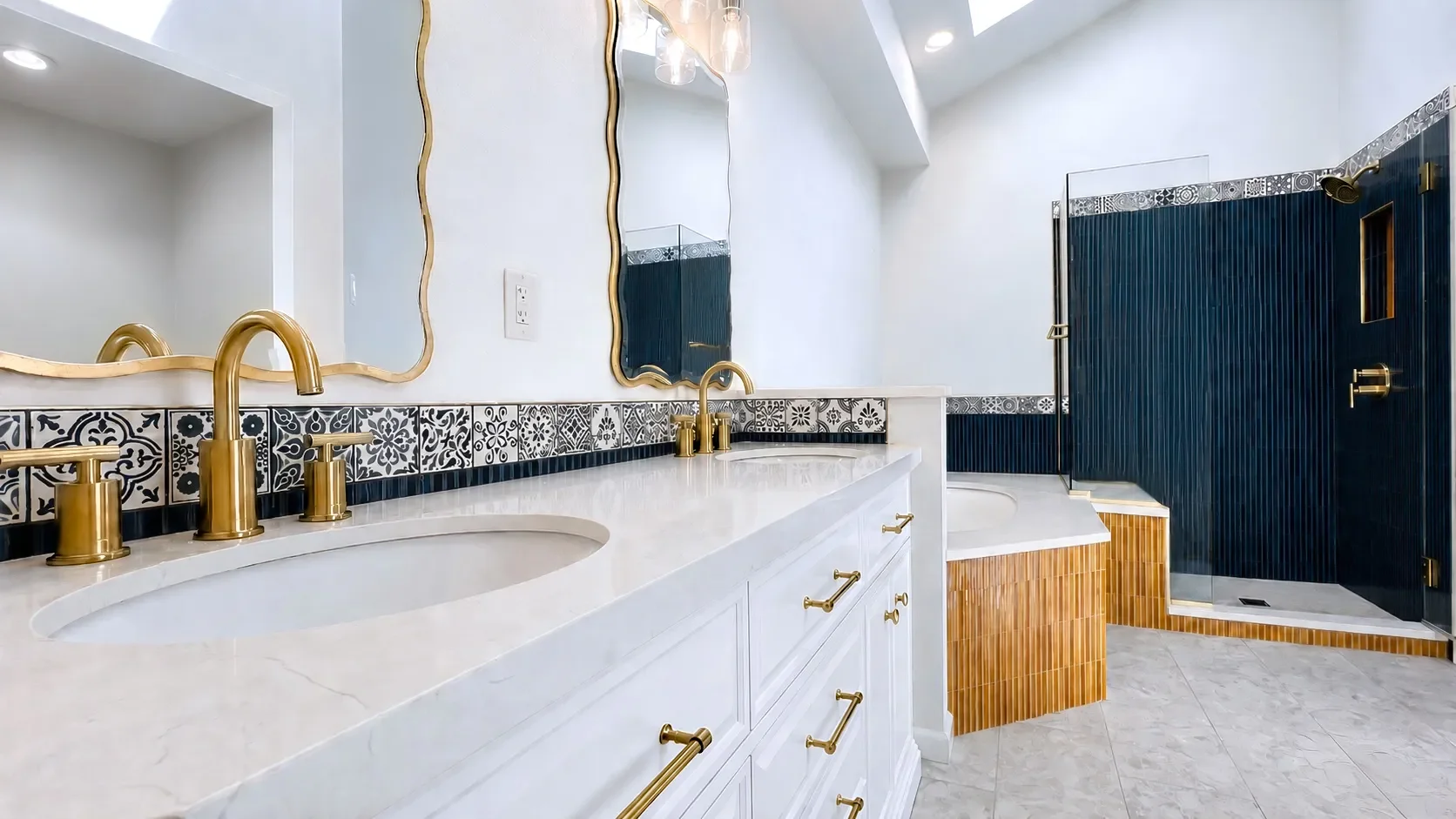 Luxury contemporary art deco master bathroom remodel by Downy Home Remodeling featuring contrasting bold blue and yellow soldiered tile with patterned accent tile cap, white vanity with gold fixtures, large quartz counter soaking tub, & seated shower