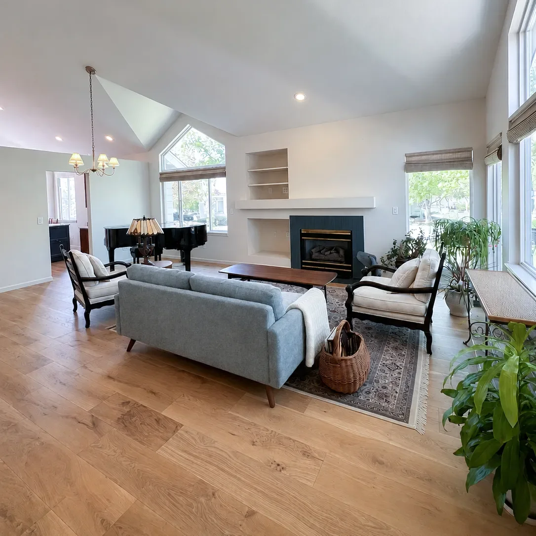 View of living room in newly remodeled Gunbarrel, CO home, featuring vaulted ceilings, recessed accent lighting, freshly tiled fireplace, and newly installed white oak hardwood floors.