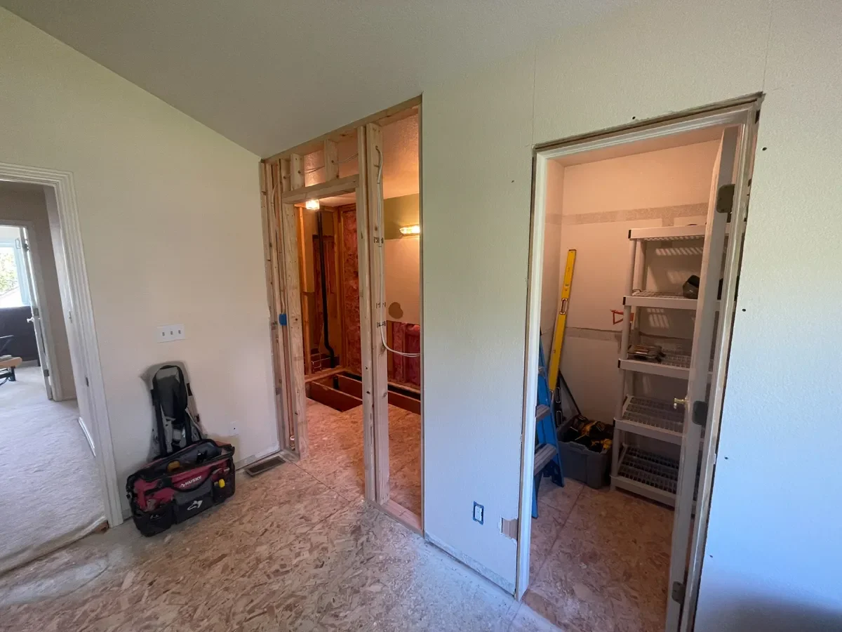 Master bedroom and bathroom under construction in a Gunbarrel, CO home remodel, showcasing newly built wall between bedroom and bathroom and a reconfigured closet entrance
