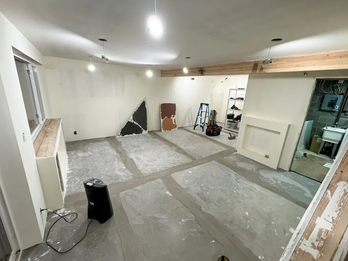 Basement remodel in Boulder, CO showing unfinished progress with primed drywall, unfinished concrete floors, and exposed ceiling beam