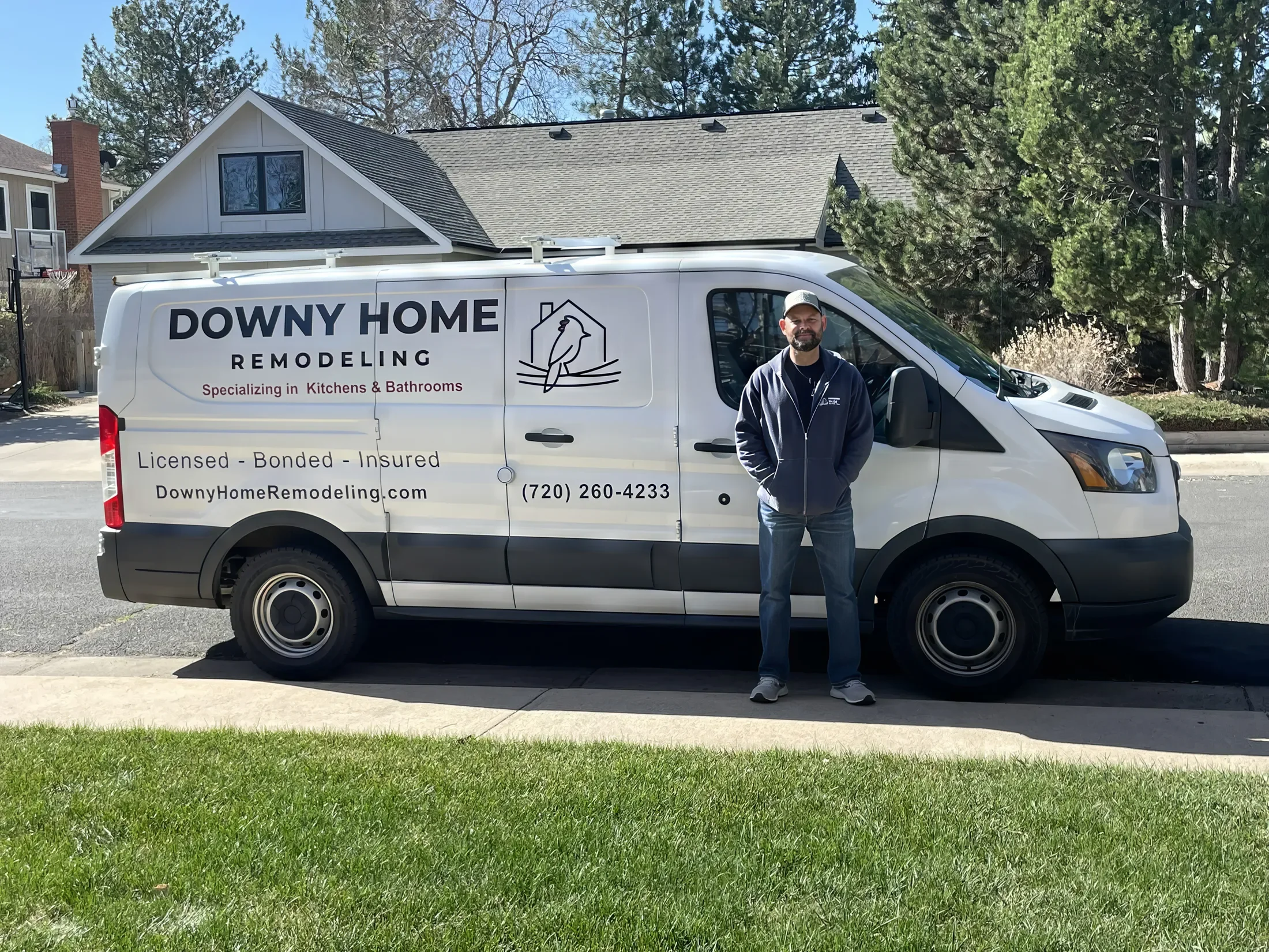 Wayne Mullis, owner of Downy Home Remodeling, stands outside next to a company van branded with business logo