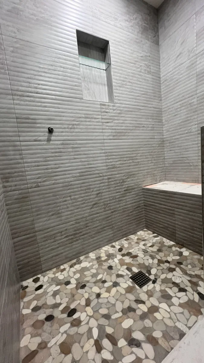 Freshly grouted pebble mosaic tile shower floor in a Gunbarrel, CO guest bathroom remodel in progress