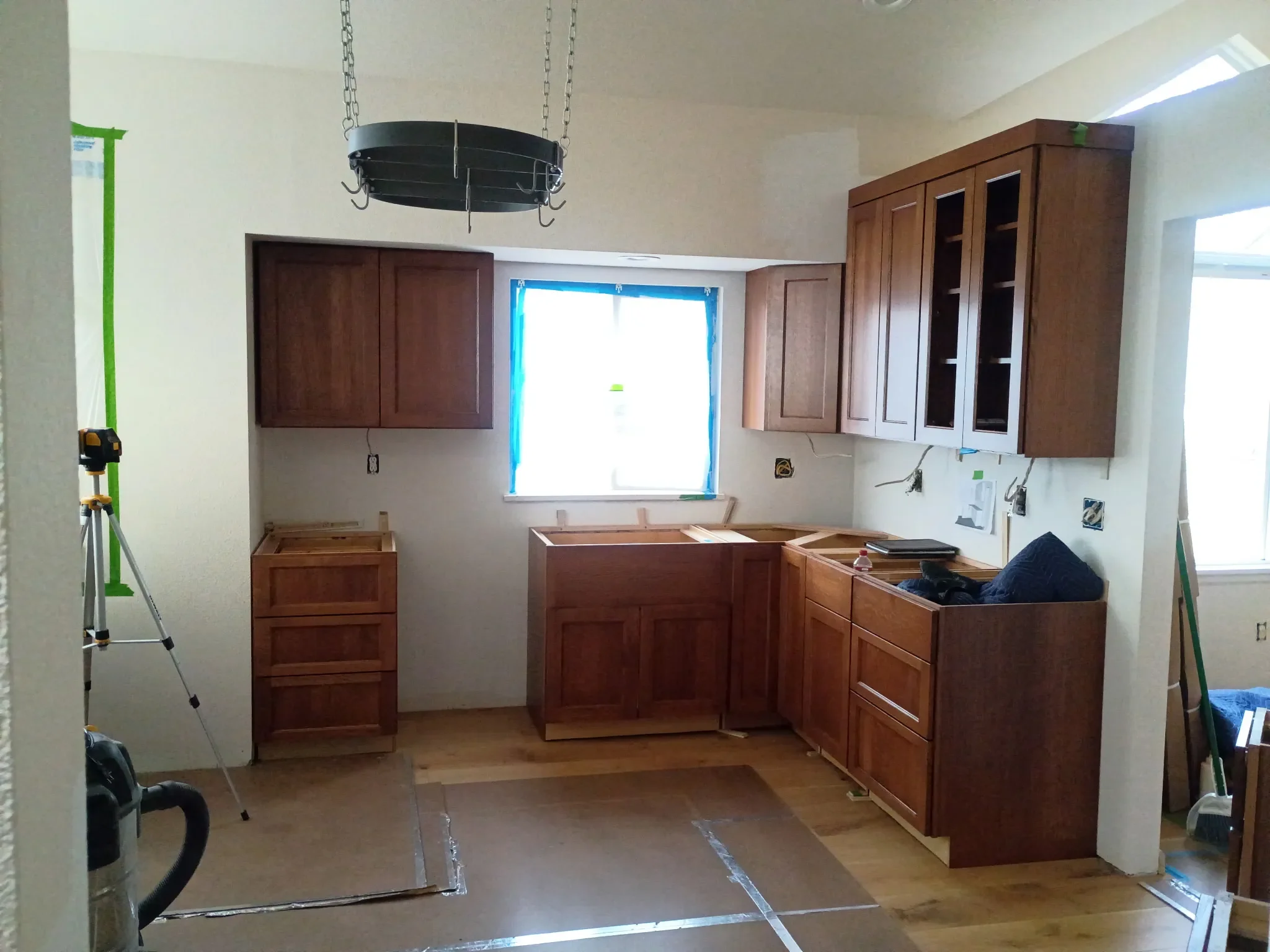 Kitchen interior under renovation in Gunbarrel, CO featuring unfinished custom cabinet build, exposed electrical wires, and protected hardwood floors