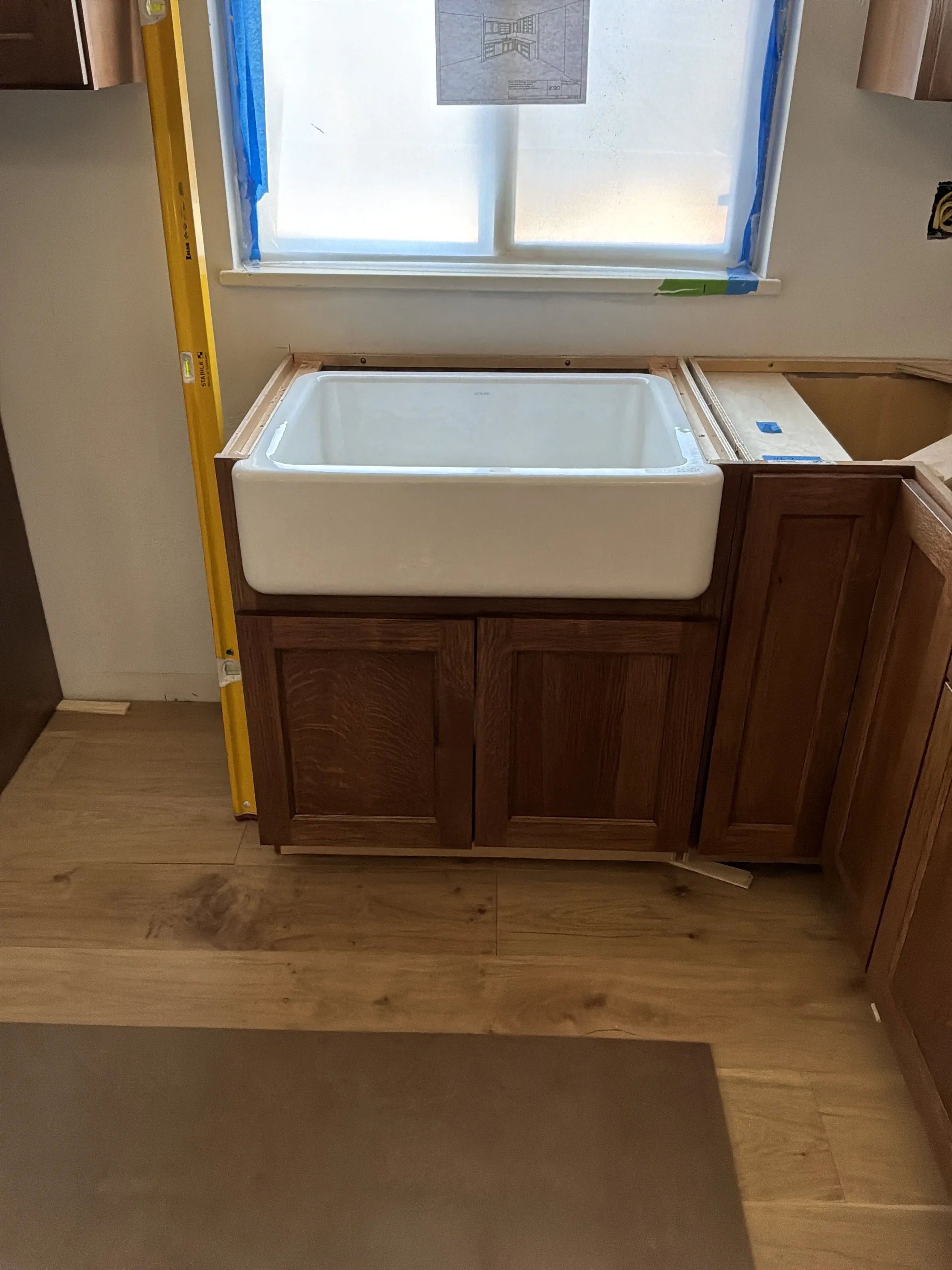 Newly installed white farmhouse sink without fixtures or countertop in an unfinished kitchen remodel in Gunbarrel, CO