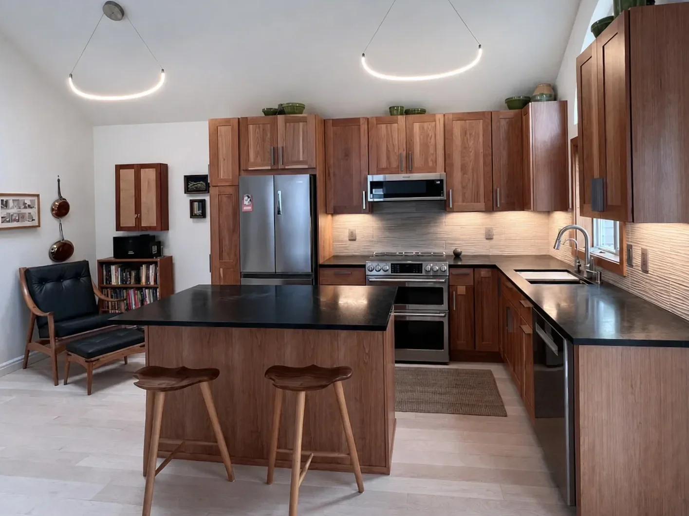 Completed kitchen remodel in Newlands, North Boulder, CO featuring custom cherry wood shaker cabinets, textured tile backsplash, green soapstone countertops, vaulted ceilings, and light colored vinyl plank flooring
