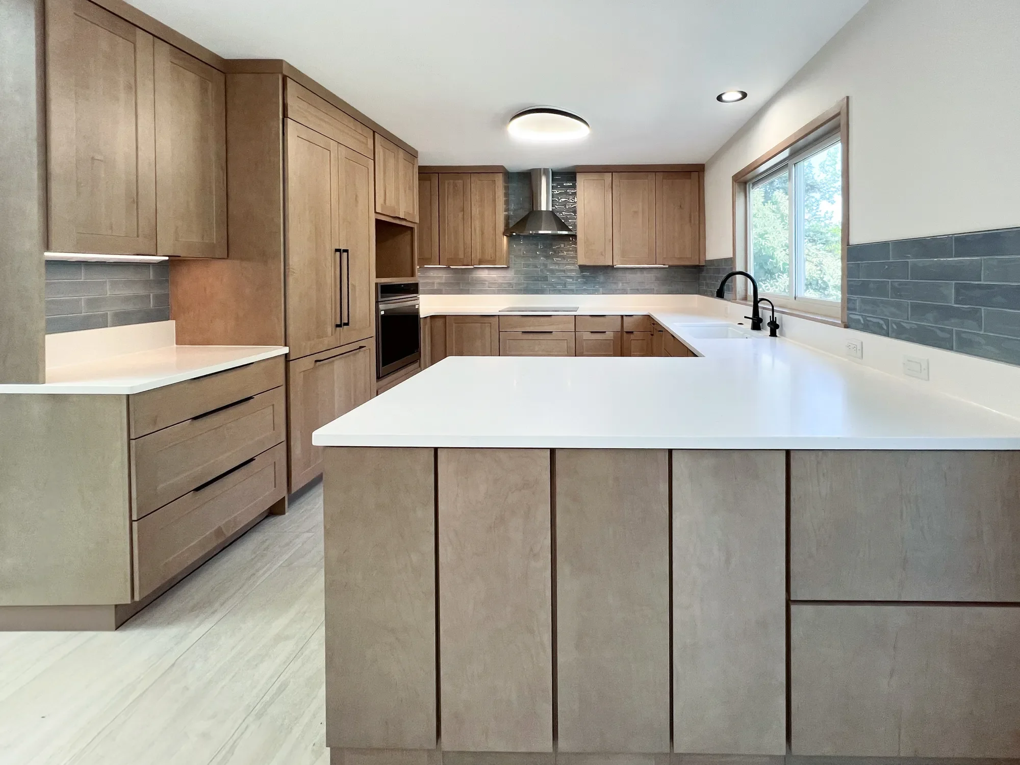 Completed contemporary craftsman kitchen remodel in Boulder, CO featuring oak custom cabinets with additional dining room storage, white quartz countertops, blue subway tile backsplash, and undercabinet LED lighting
