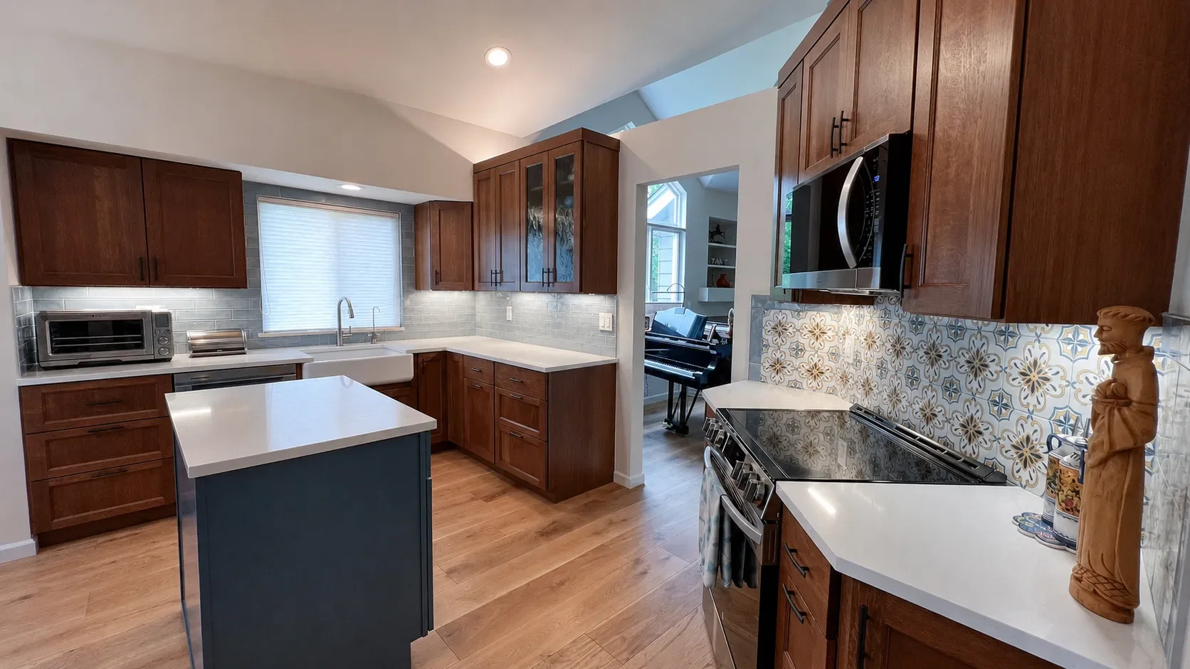 Gunbarrel, CO contemporary craftsman style completed kitchen remodel featuring custom cherry wood cabinets, patterned tile backsplash, farmhouse undermount sink, and blue mobile cabinet island with white quartz countertop