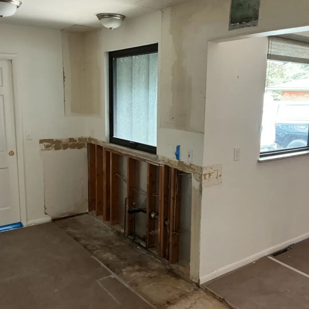 Kitchen interior under renovation in Longmont, CO, featuring newly installed window, newly repaired drywall and subfloor, and rerouted plumbing by Downy Home Remodeling.