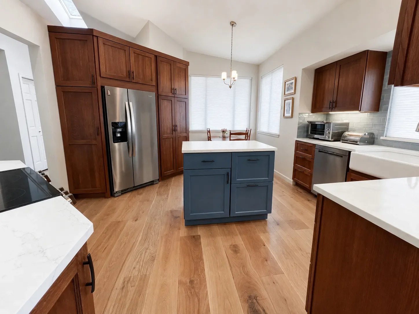 Kitchen view of a full home remodel in Gunbarrel, CO featuring a wall of custom cherry cabinets around a stainless steel fridge and three separate counter areas including a mobile blue quartz top island storage cabinet