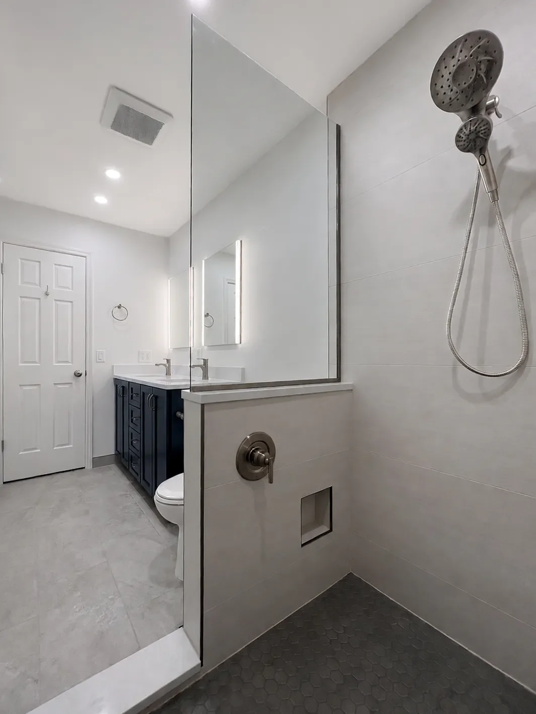Contemporary bathroom remodel in Table Mesa Boulder, CO, view of interior shower with brushed nickel fixtures, shaving niche, foot niche, and hexagon mosaic floor tile