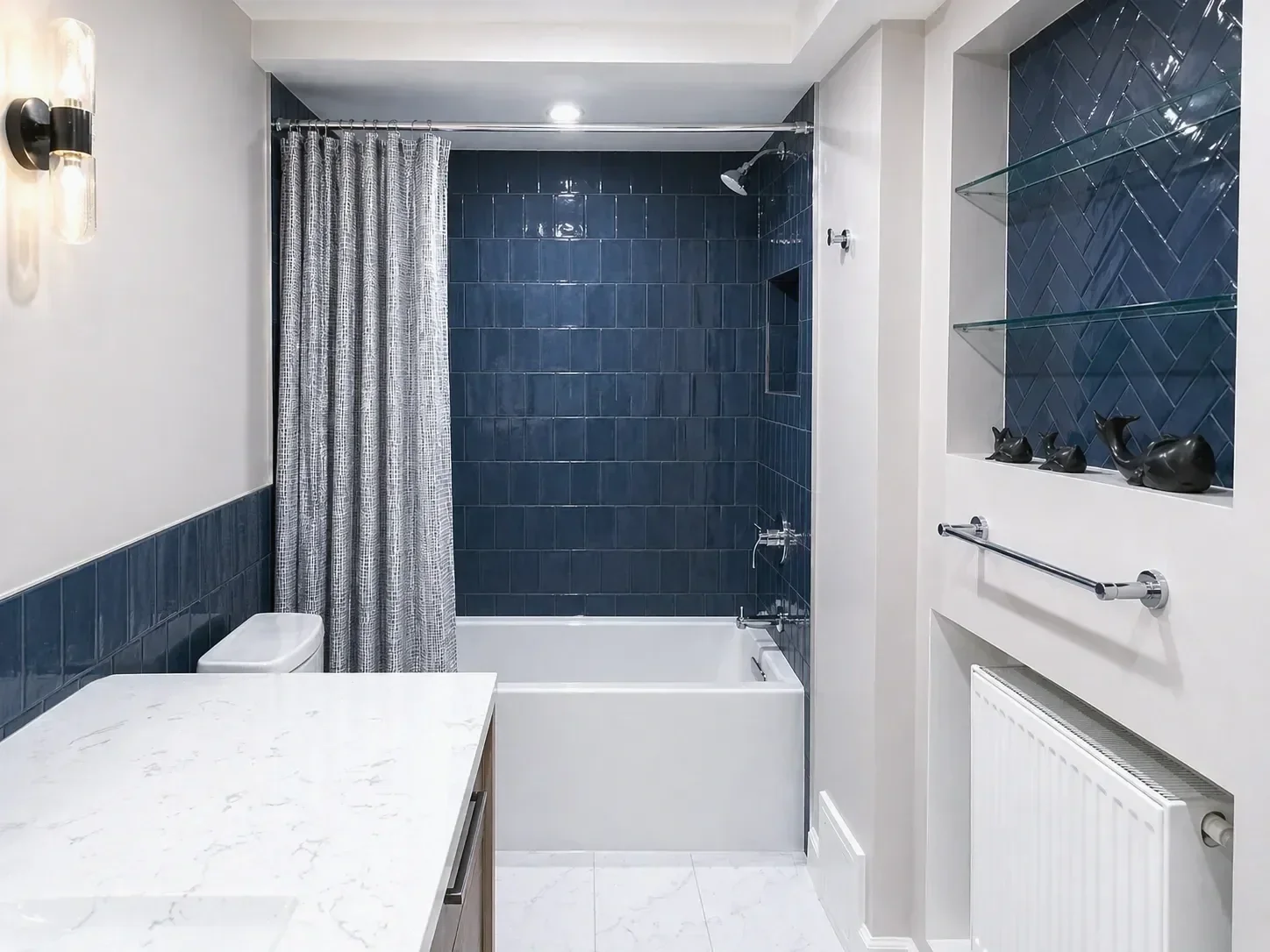 View of completed contemporary bathroom remodel in Boulder, CO with marble floors, marble vanity countertop, soaking bathtub, and bold blue shower tile, tile wainscoting, and herringbone tiled wall niche