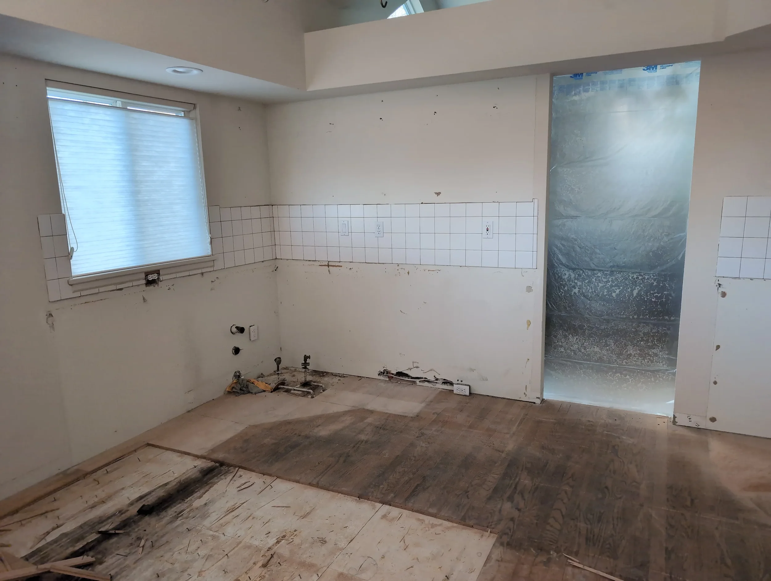 Demolition of kitchen in Gunbarrel, CO featuring plastic dust protection and cabinet removal, a remodel in progress.