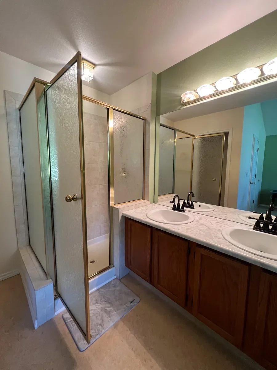 Master bathroom in Gunbarrel, CO before renovation with a brass framed walk-in shower, suboptimal layout, laminate vanity countertops and outdated lighting fixures