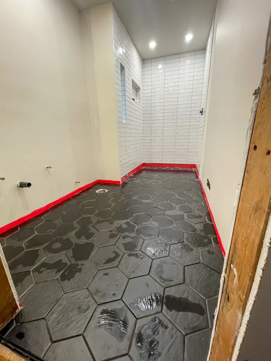 Bathroom floor freshly tiled with dark gray hexagon stone floor tiles in Superior, CO partially completed bathroom remodel