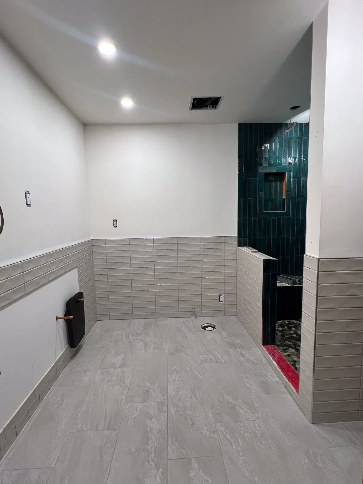 Boulder, CO bathroom during remodel process, halfway finished but missing shower glass, toilet, vanity, and mirror. 