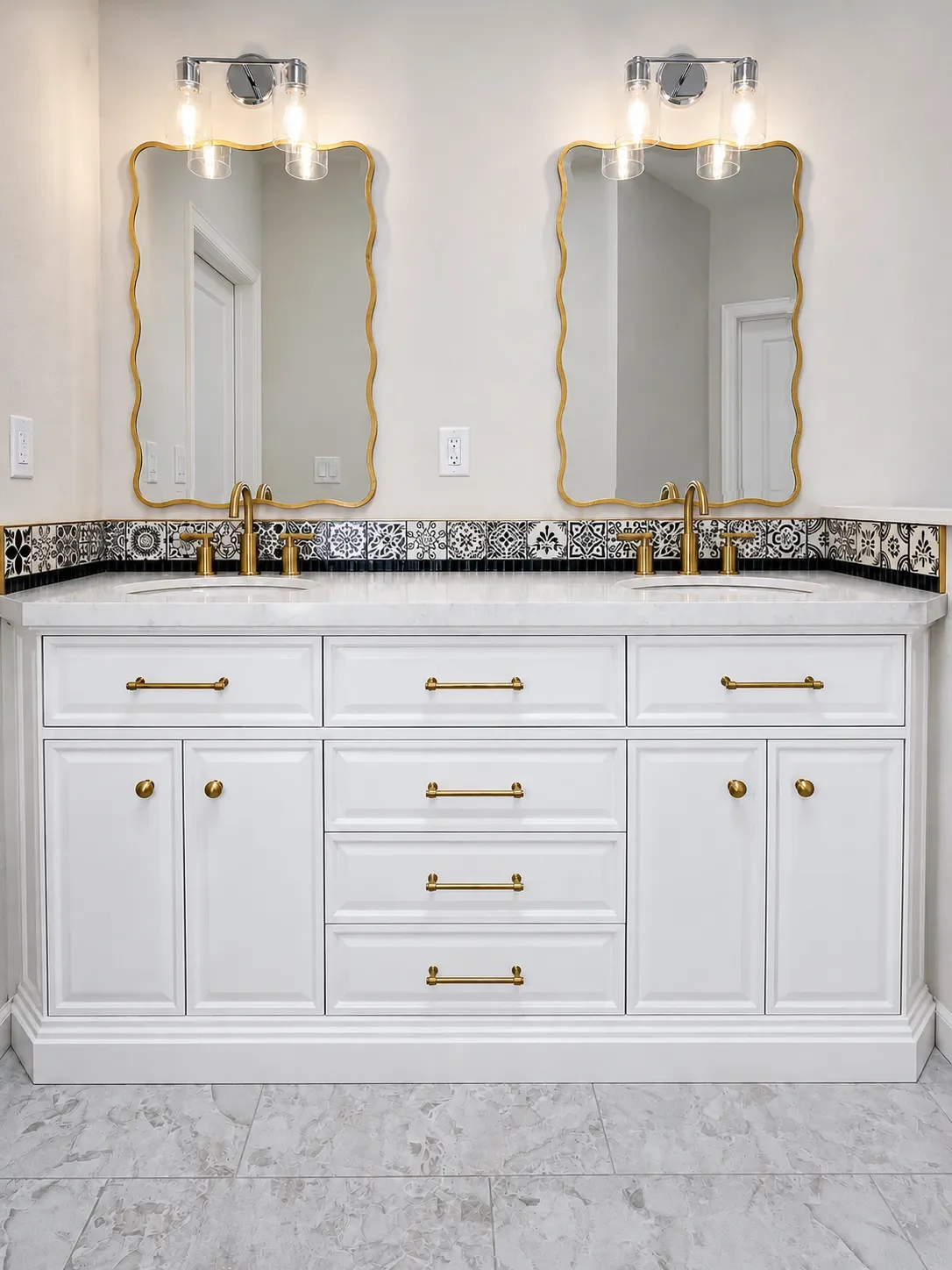 Modern white bathroom custom vanity with art deco gold scalloped edge mirrors and pattern tile backsplash in a master bathroom remodel by Downy Home Remodeling