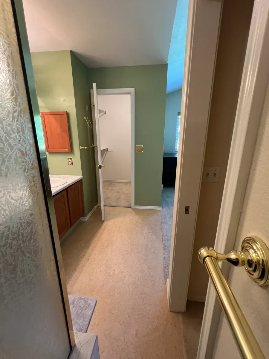 Master bathroom before renovation in Gunbarrel, CO, view of swinging closet door opening into bathroom floorplan from the vantage point of a confined empty space beside the walk-in shower