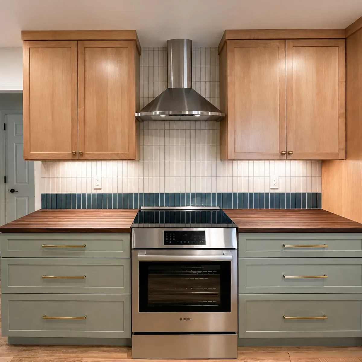Stainless steel induction stove and range hood, maple cabinets, and dark premium walnut butcher block countertops in a Longmont, CO kitchen remodel by Downy Home Remodeling