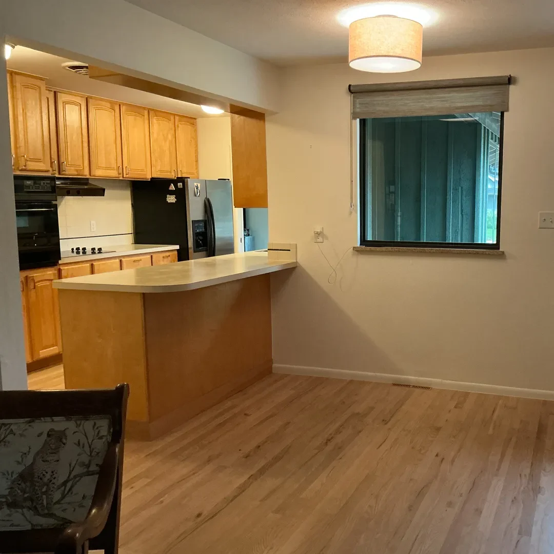 View of kitchen and adjacent entryway in a Longmont, CO home awaiting renovation, showcasing previous wasted space and cluttered kitchen cabinetry