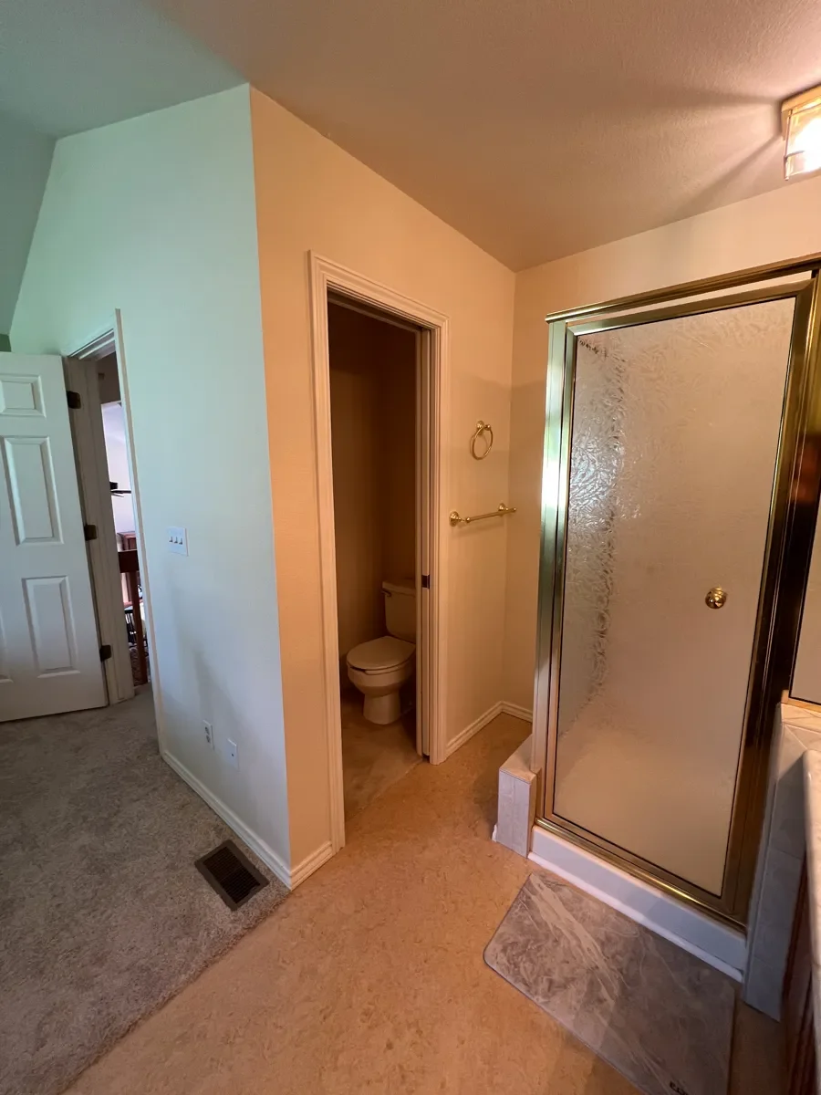 Gunbarrel, CO master bathroom before being remodeled, showing open doorway between bedroom and bathroom, awkward shower placement, confined water closet, and inefficient use of space