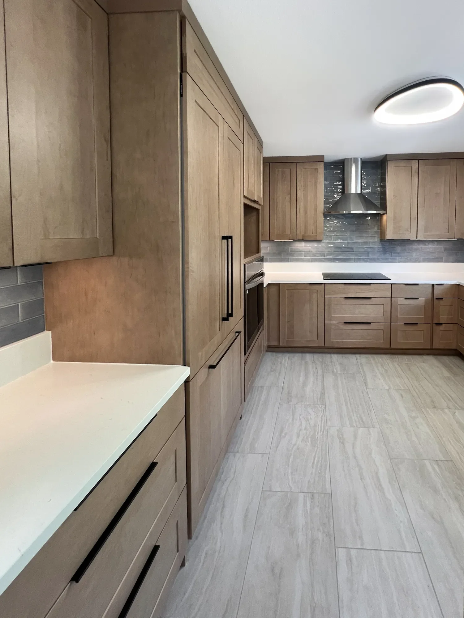 Kitchen remodel in Boulder, CO featuring custom conceal panel oak cabinets, light blue subway tile backsplash, undercabinet LED lighting, and kitchen secretary counter station