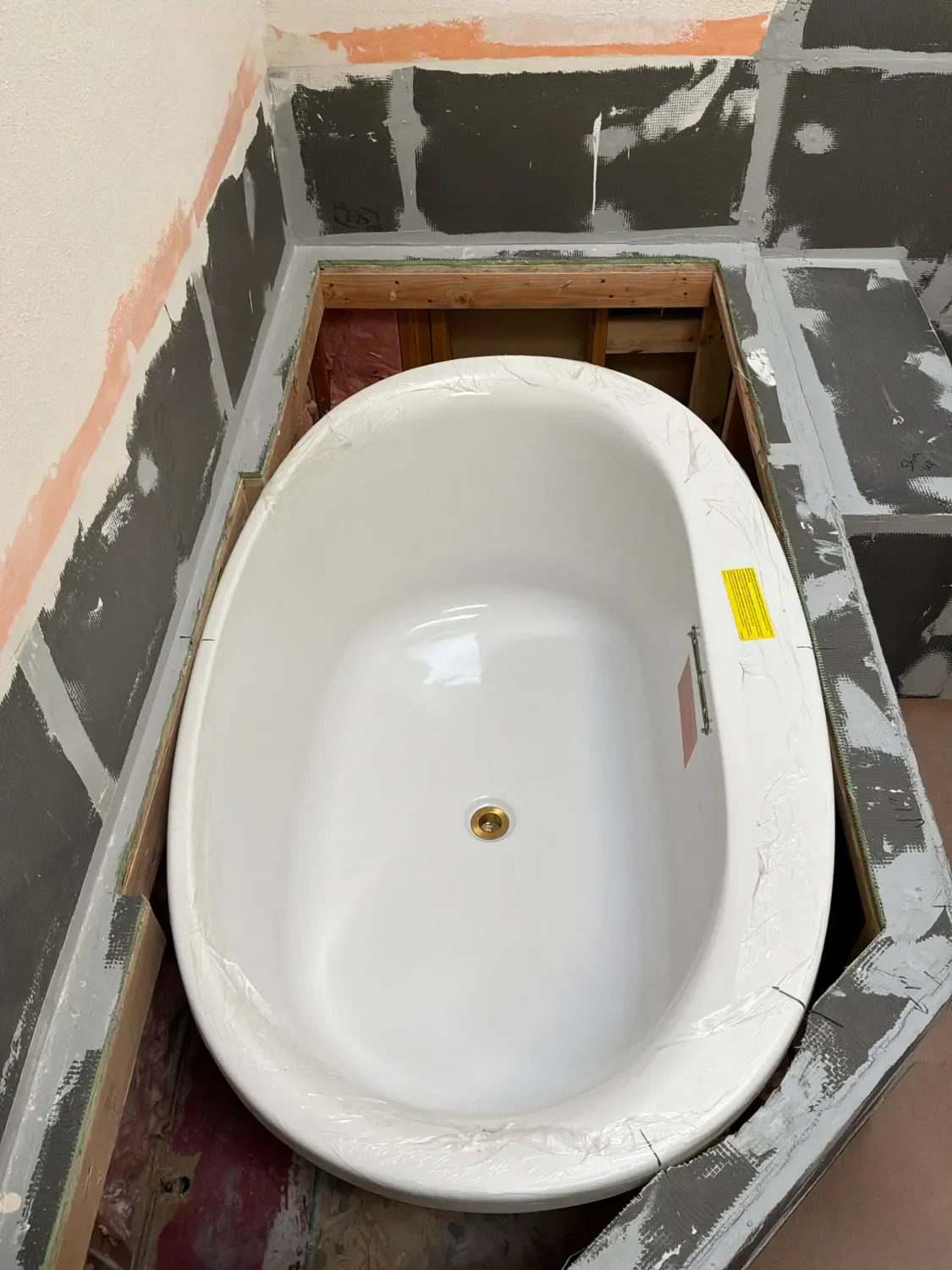 Newly installed white oval Kohler acryclic soaking tub in a bathroom remodel in progress in Gunbarrel, CO