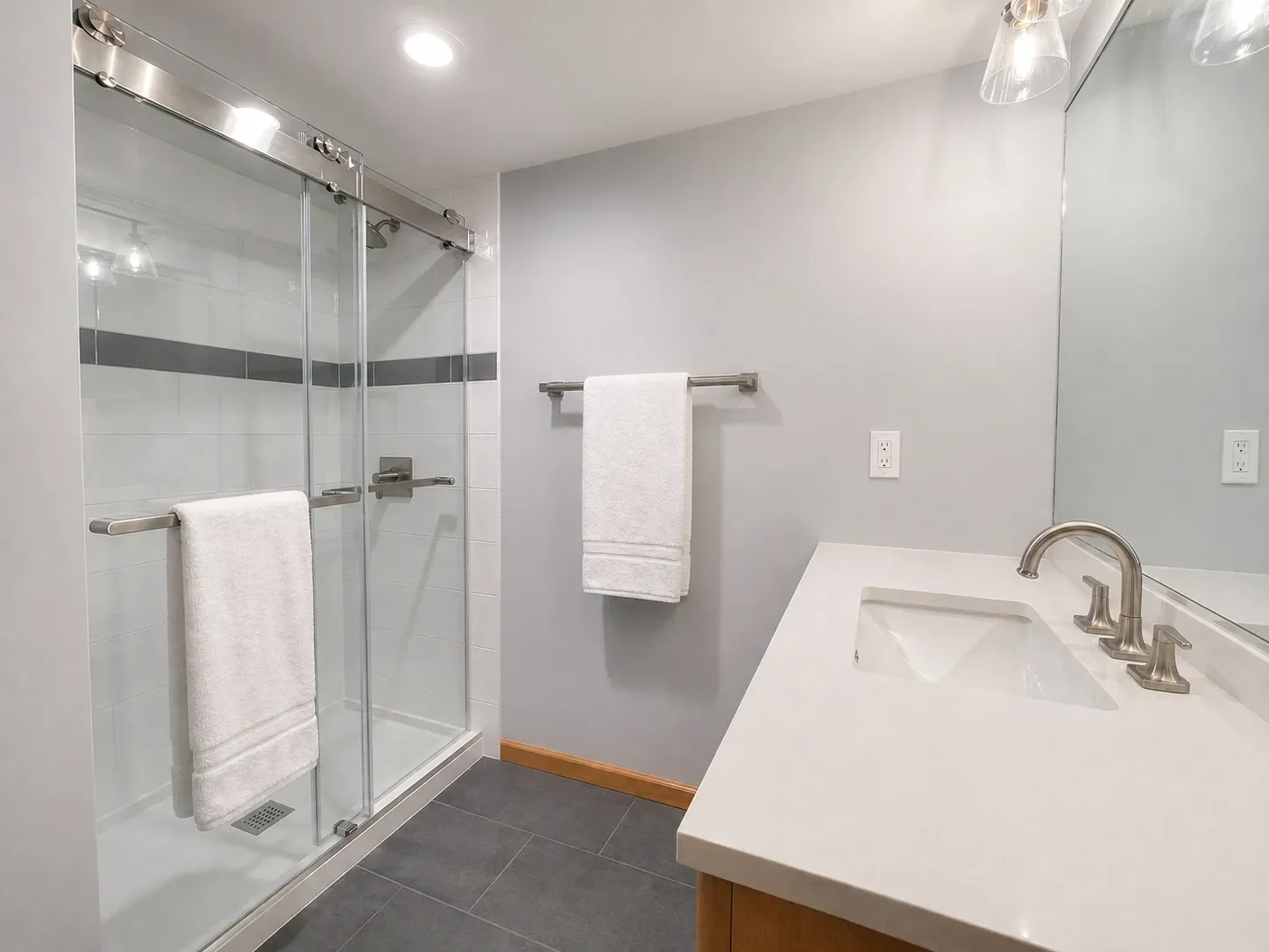 Remodeled contemporary style budget bathroom in Niwot, CO featuring vanity with white quartz countertop and walk-in shower with frameless glass sliding door