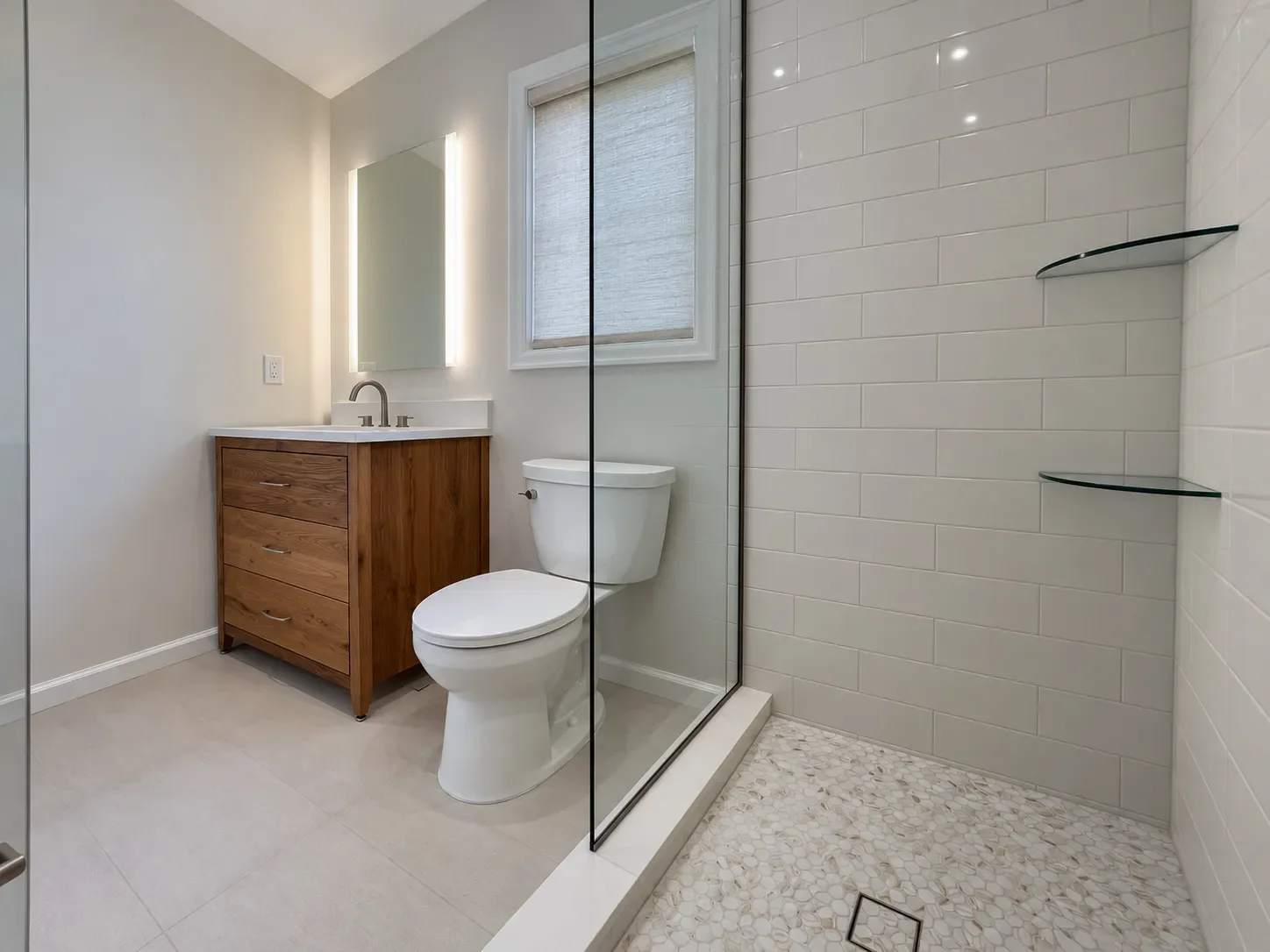 Minimal contemporary bathroom remodel in Boulder, CO viewed from inside framless glass walk-in shower, with white mosaic shower floor tile, large format linen look floor tile, reclaimed white oak barnwood single vanity, and dimmable LED mirror