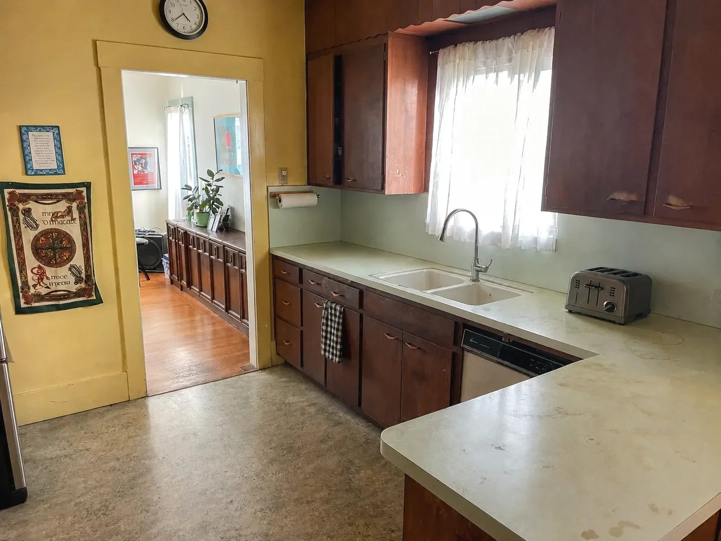 Outdated vintage kitchen before renovation in Lafayette, CO with yellow walls, scalloped red wood cabinets, and linoleum floors