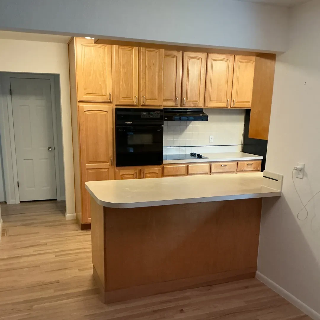 View of original, narrow kitchen peninsula with laminate countertops and honey oak stained cabinetry in a Longmont, CO kitchen before being remodeled