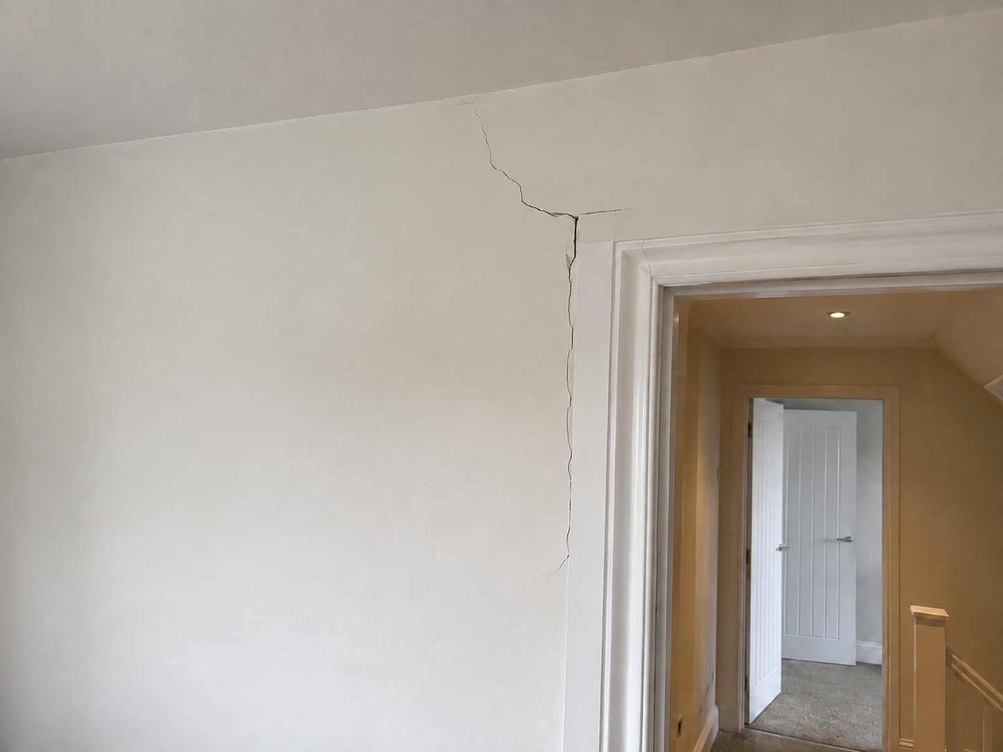Crack in the upper corner of an interior wall near the doorway.