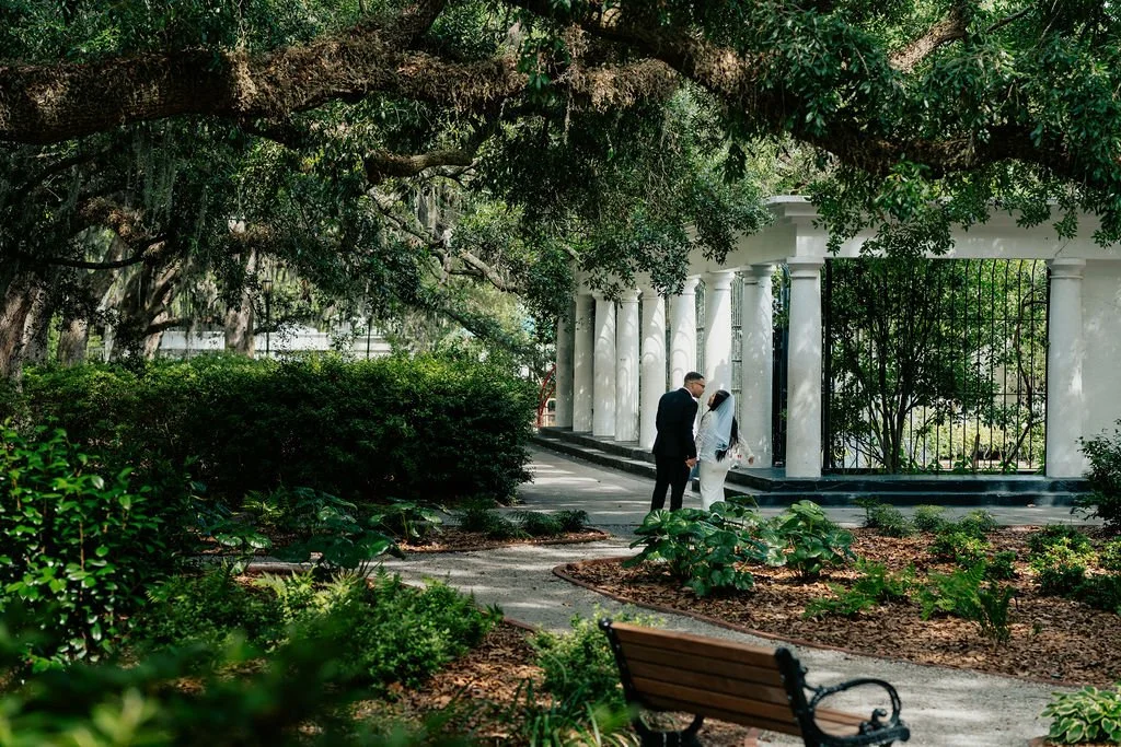 Savannah GA just married wedding couple candid walking away in Forsyth Park Shade Garden under Spanish moss cinematic wedding photography by ARG Foto