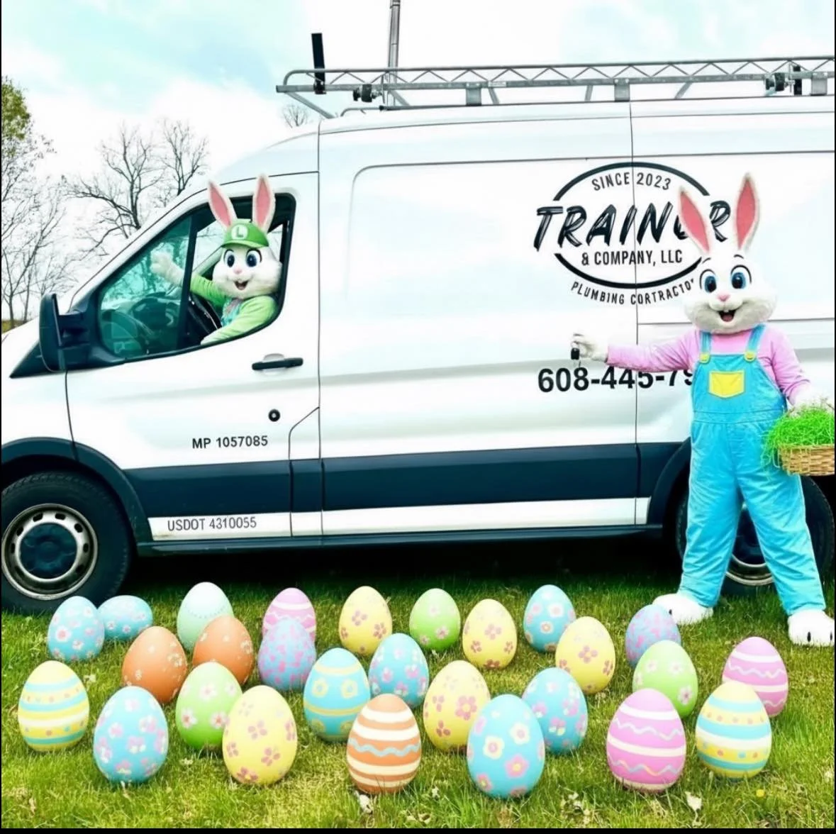 Easter Bunny characters with a decorated Easter eggs on the grass near a white service van with Easter-themed signage and mascot costumes, celebrating Easter.