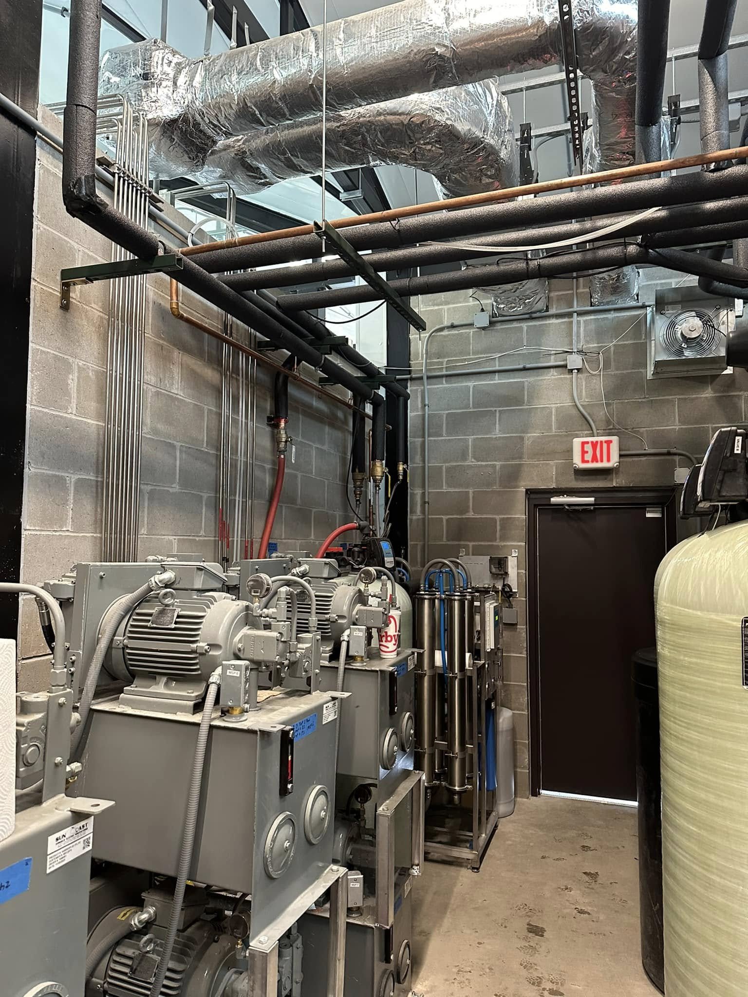 Industrial mechanical room with equipment, pipes, and ductwork.