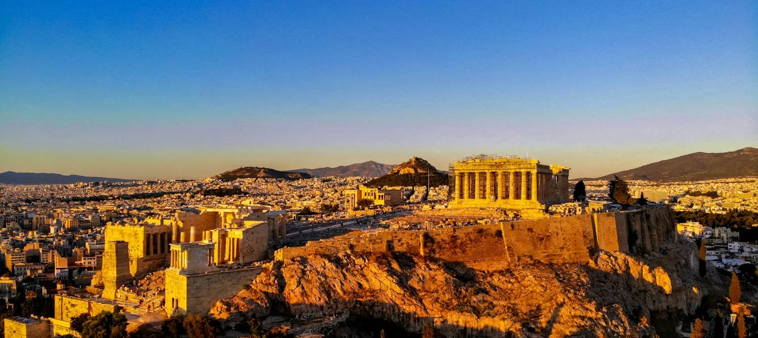 Sunset view of the Acropolis in Athens, Greece, with the Parthenon on a rocky hilltop overlooking the city.