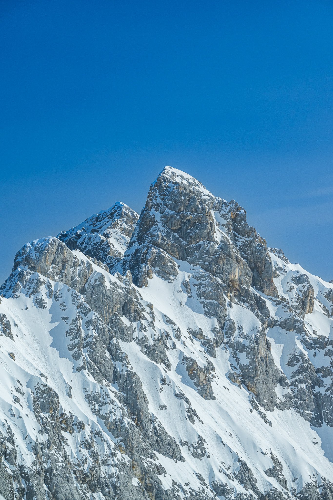 Verschneite Bergspitzen unter klarem, blauem Himmel.