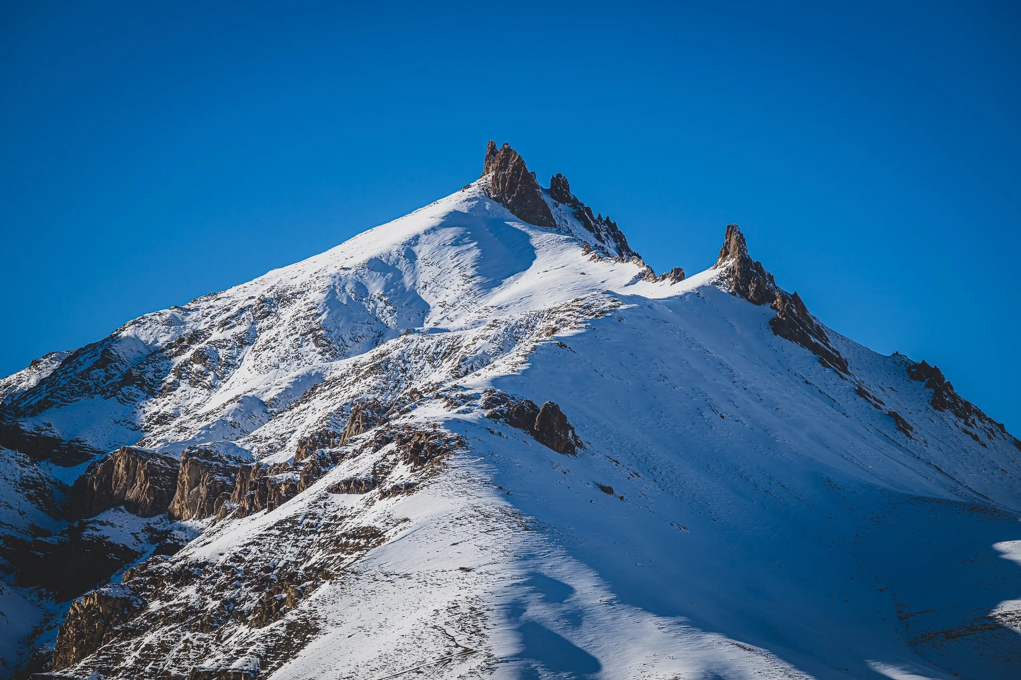 Berggipfel im Schnee bei klarem blauen Himmel.