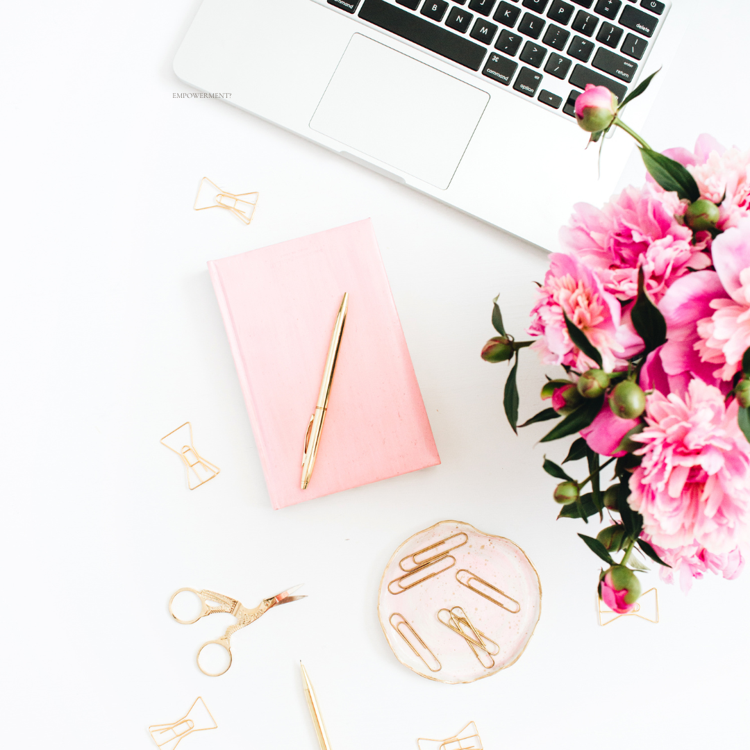 desk set up with vibrant flowers, pink notebook, supplies