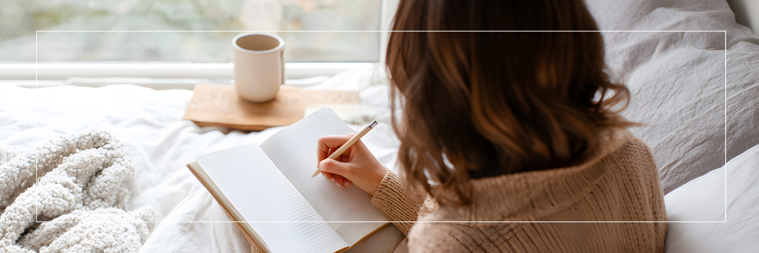 woman on couch, journaling with tea and blankets