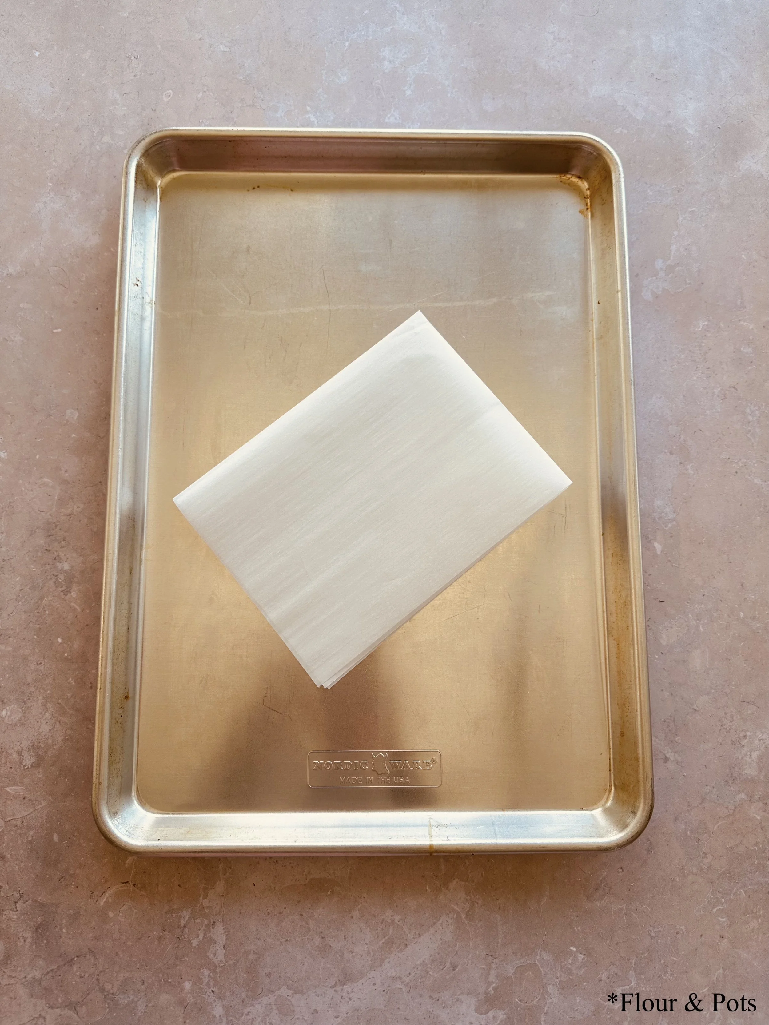 Step 3: A baking tray with parchment paper, showing the tools needed to begin freezing peaches.