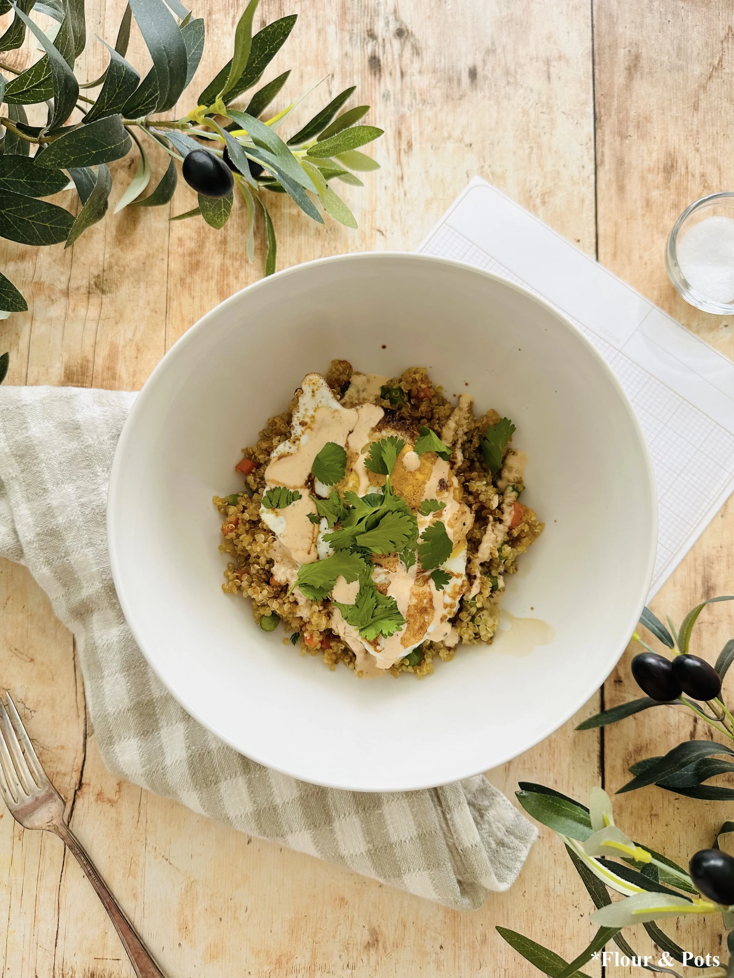 Savory quinoa breakfast bowl with fried egg and honey sriracha sauce topped with cilantro