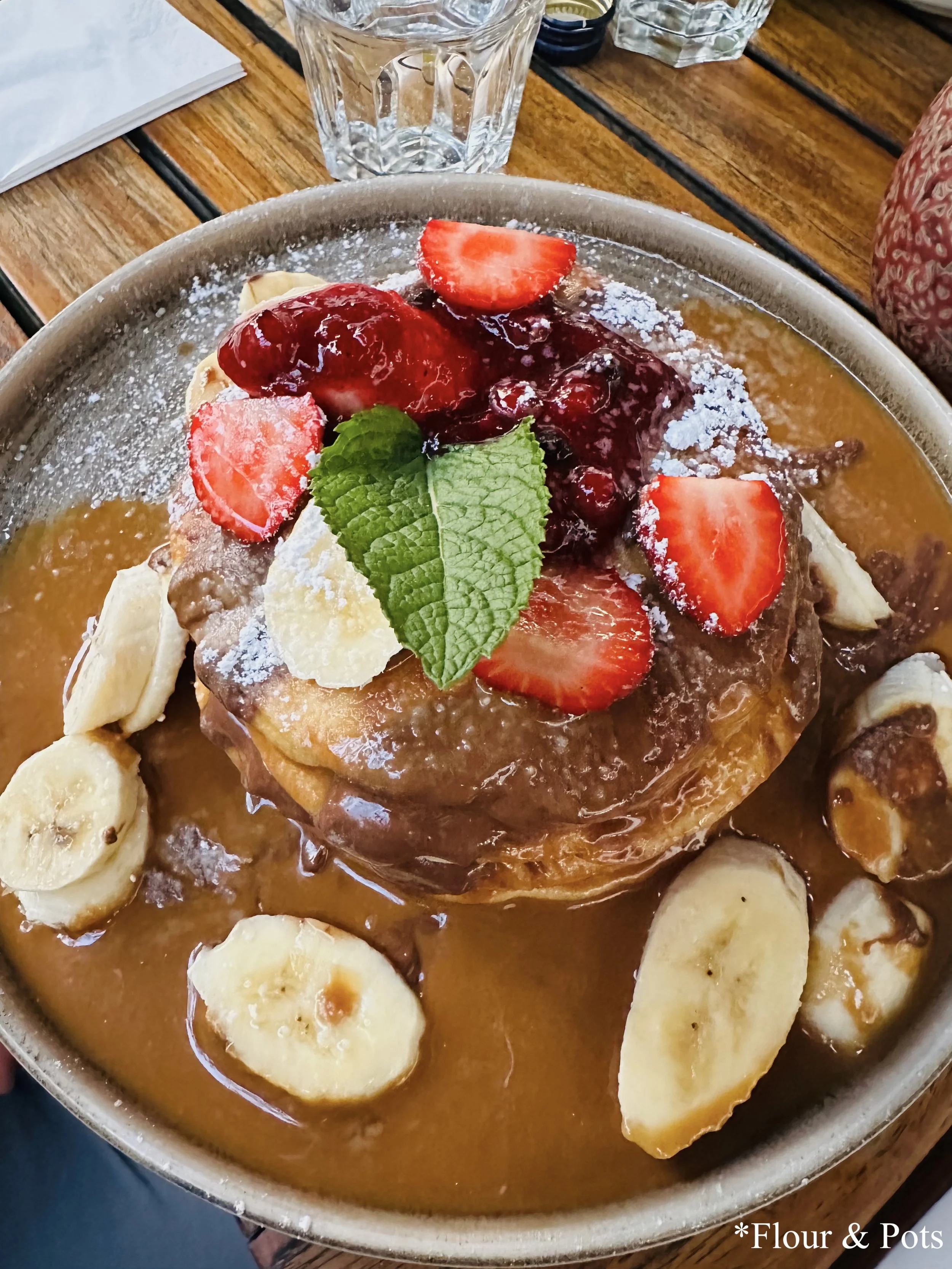 Pancake Tower Deluxe from Cotidiano in Munich, Germany, featuring layers of fluffy pancakes topped with Lotus Biscoff® cream, berry compote, nougat cream, banana, cookie crumble, and fresh fruits.