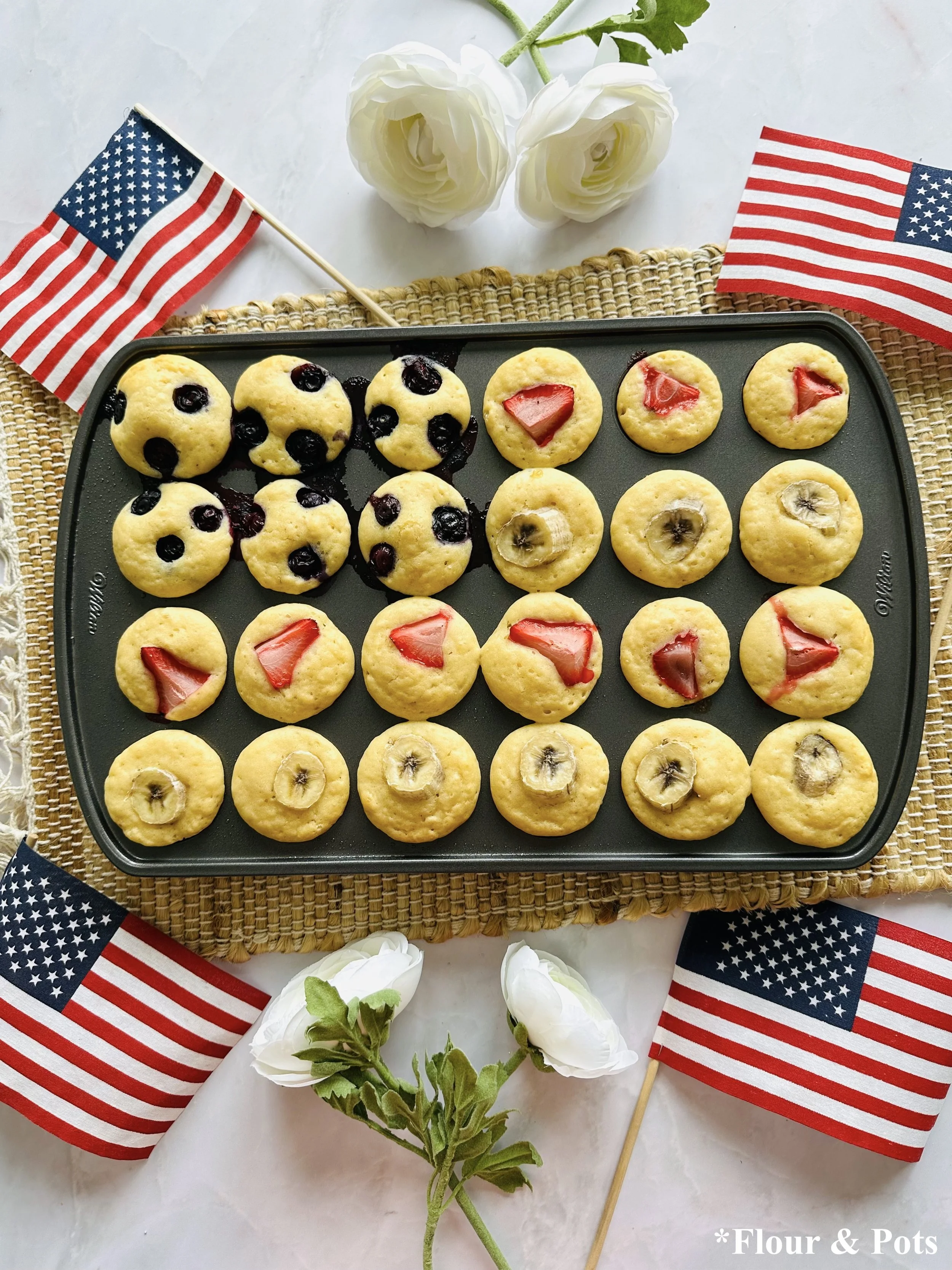 Patriotic mini pancake bites baked into an American flag with strawberries, blueberries, and bananas.