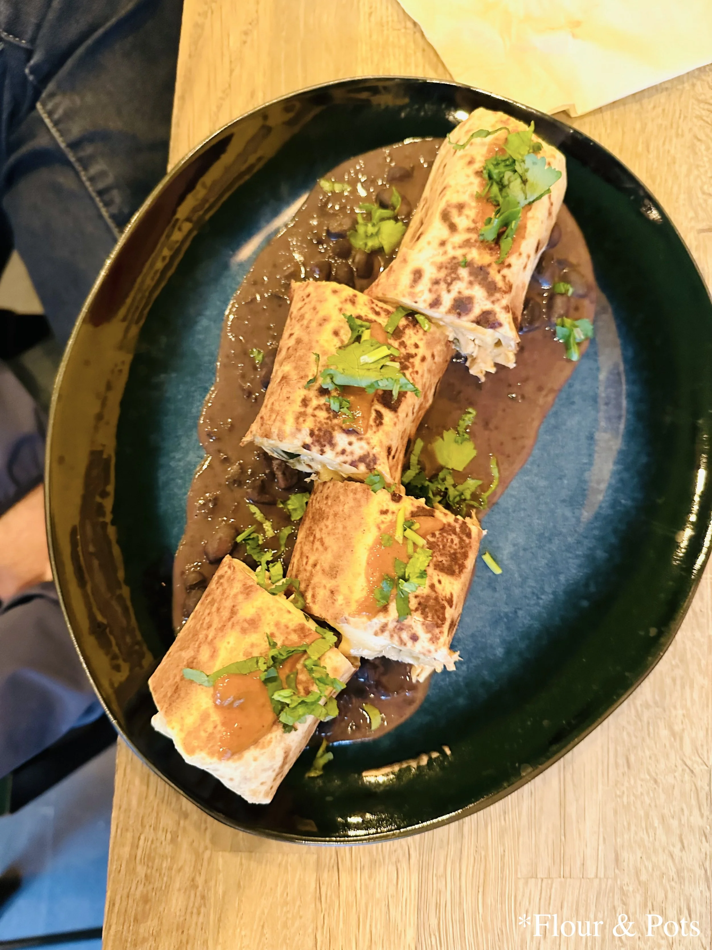Chicken burrito served on a bed of black beans and topped with cilantro from Black Beans Mexican Food in Paris, France.