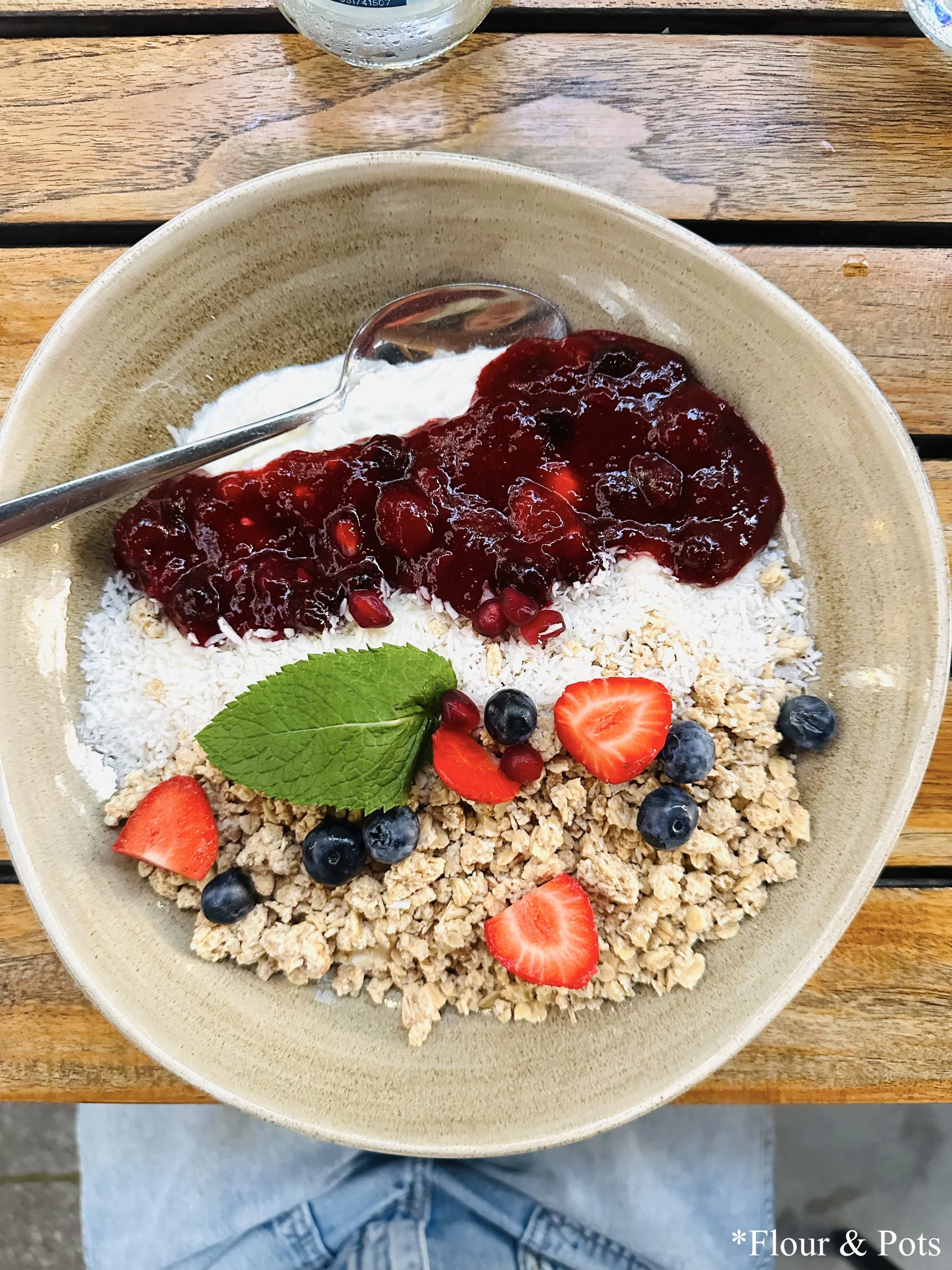 Sunny Crunch Bowl from Cotidiano in Munich, Germany, featuring natural yogurt topped with granola, banana, berry compote, coconut flakes, and fresh fruits.