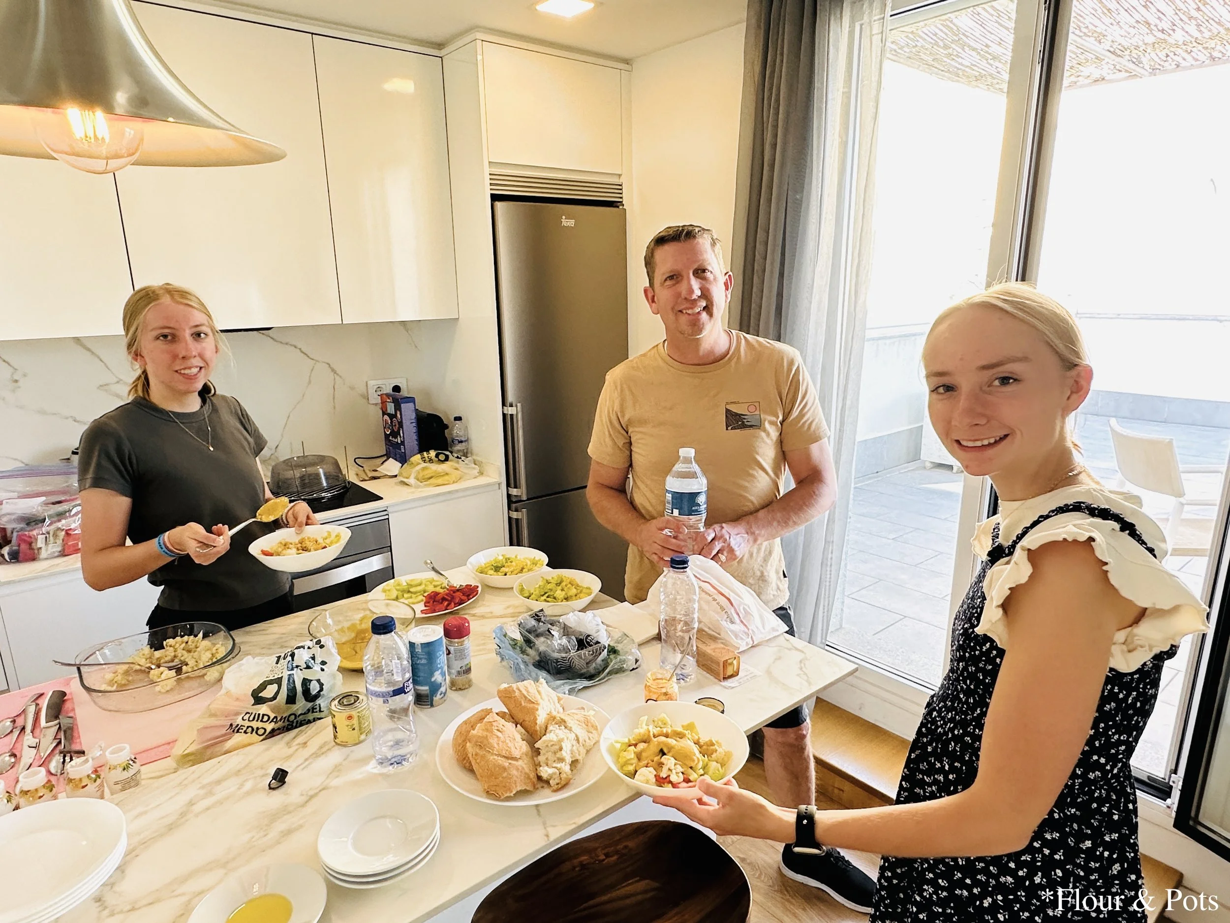 My family dishing up dinner at our Airbnb in Madrid, Spain, with bowls of veggie and honey mustard salads ready to be served.