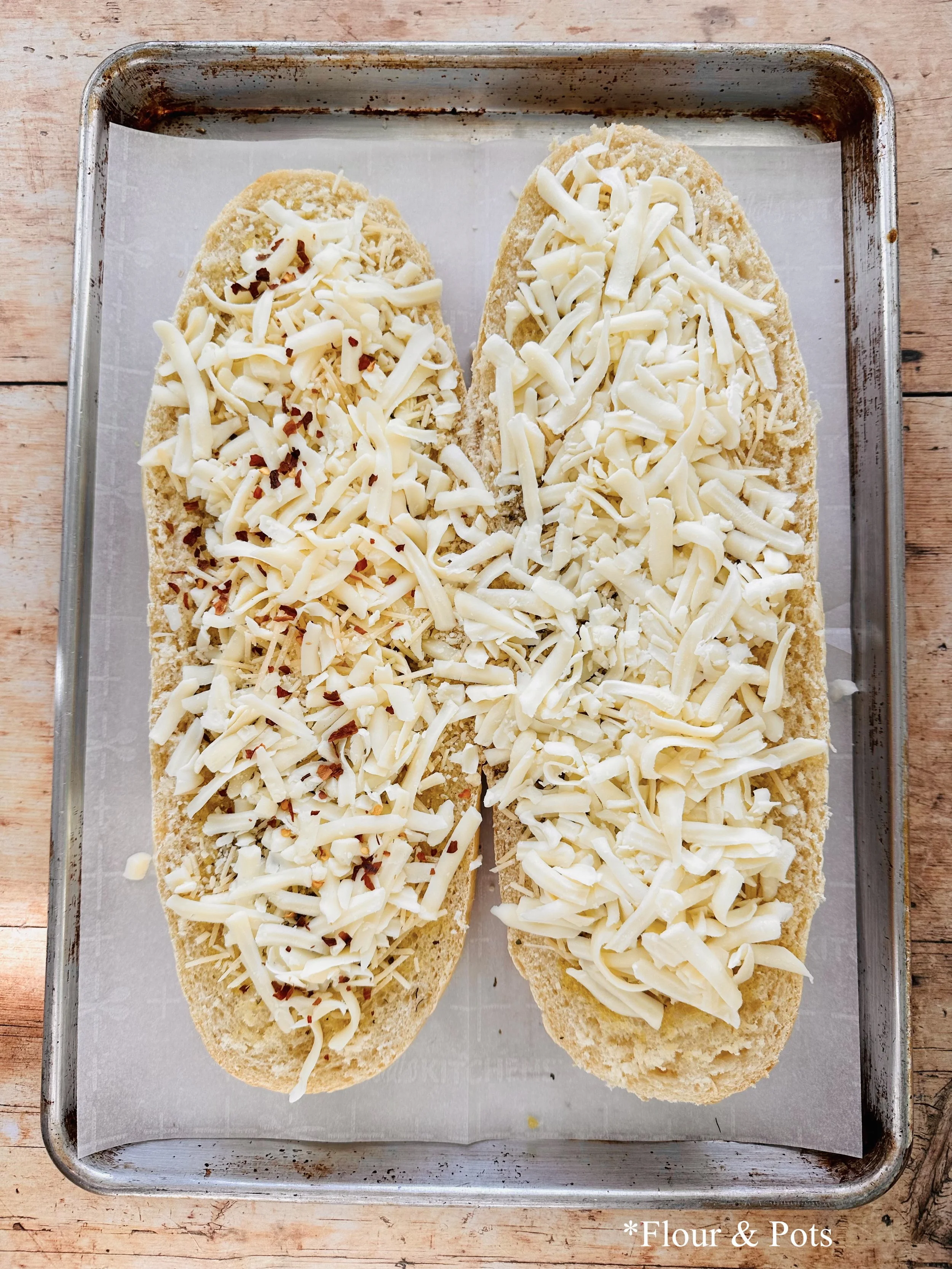 French bread pizza loaded with mozzarella, Parmesan, and a sprinkle of red pepper flakes.