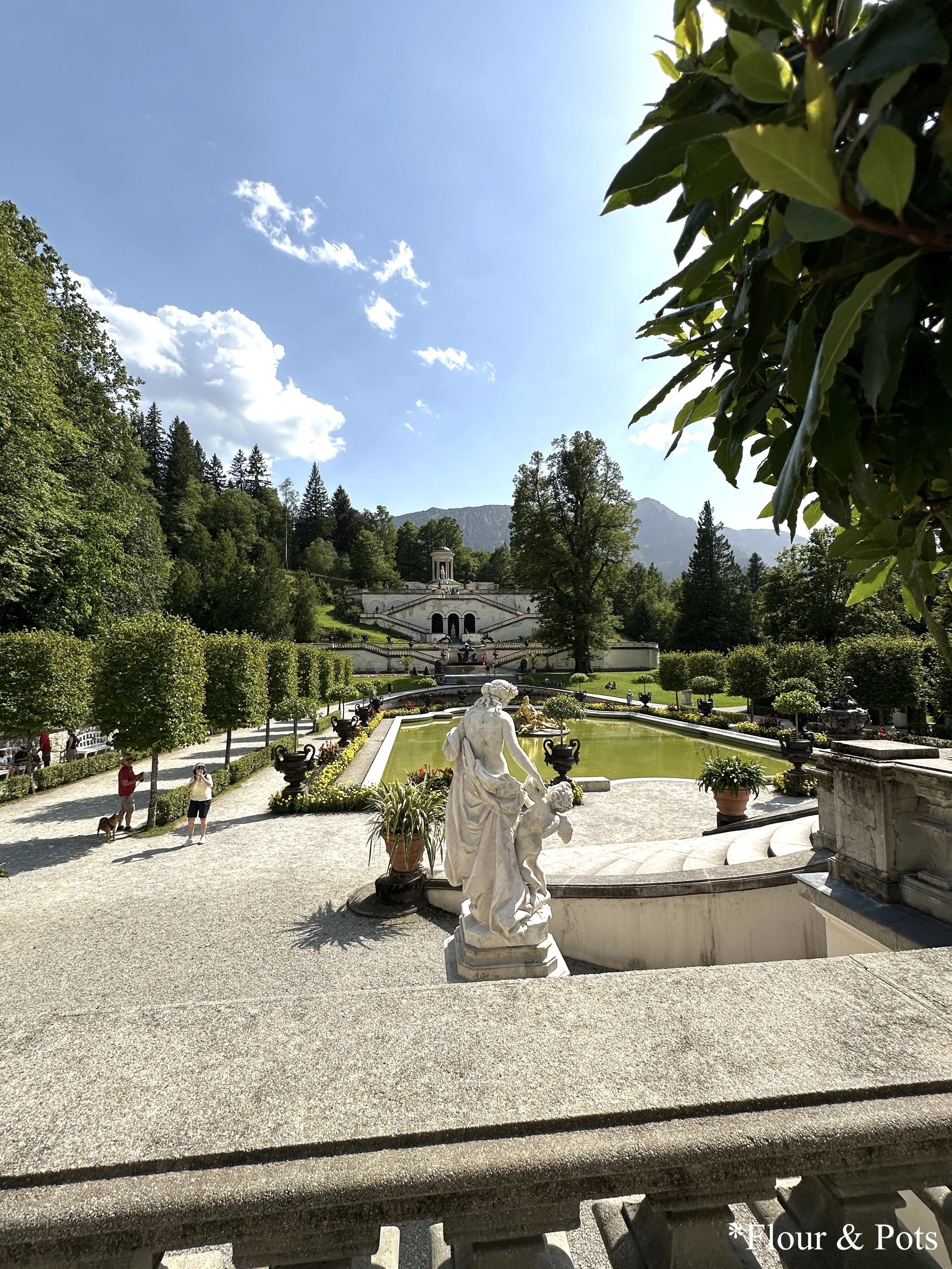 Lush garden and water parterre at Linderhof Palace, with ornate fountains and symmetrical paths.