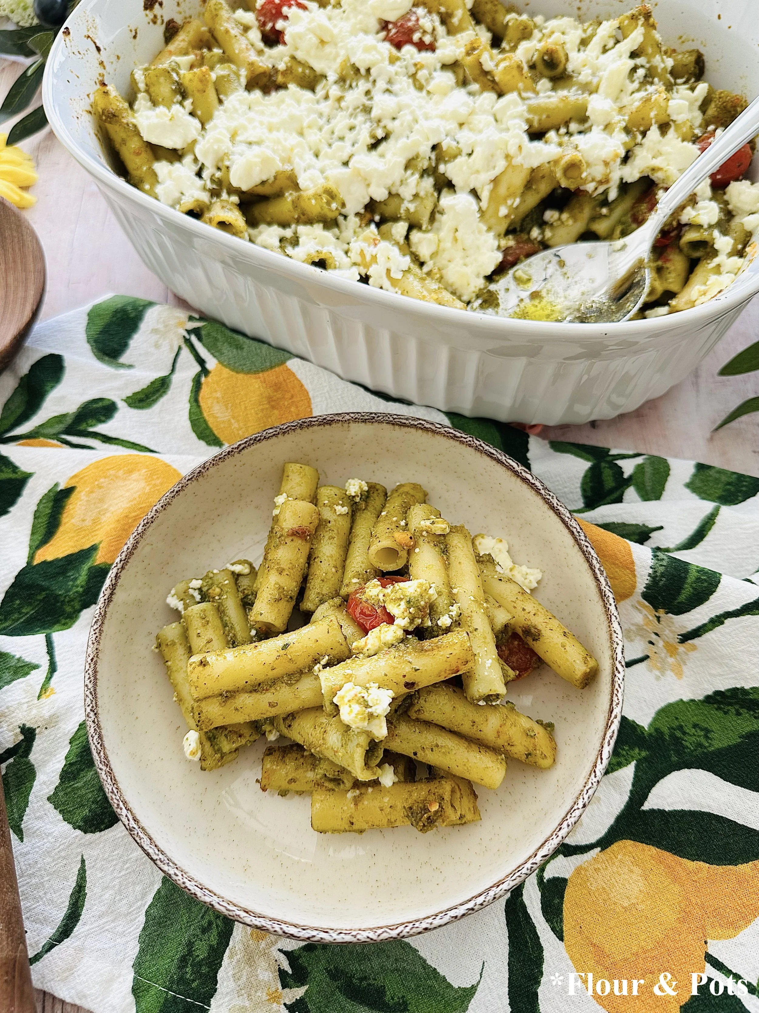 Italian summer pasta bake with pistachio pesto, roasted cherry tomatoes, and feta cheese in a baked dish