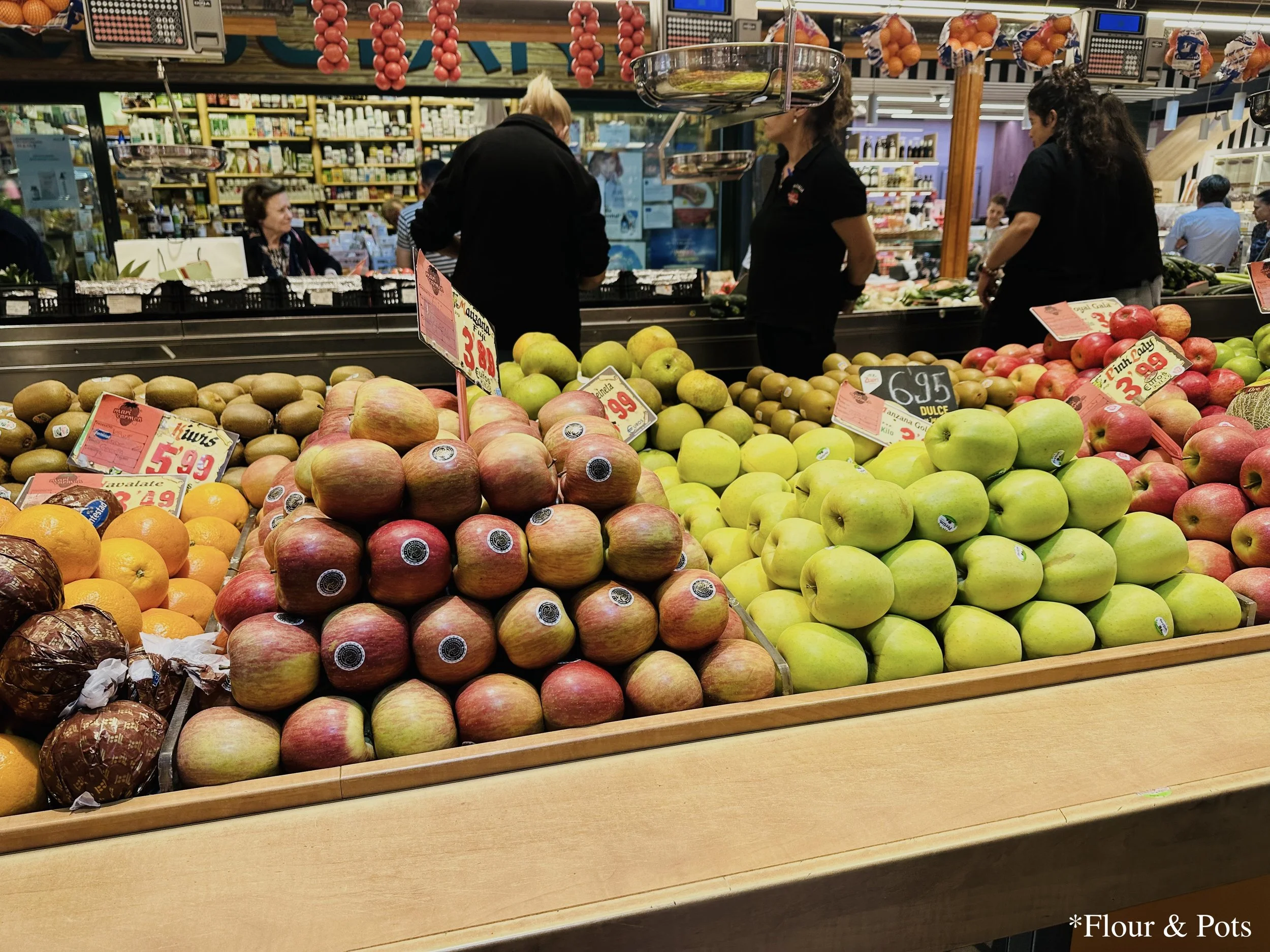 A colorful fruit stand at Mercado de la Paz in Madrid, Spain, displaying an array of fresh, vibrant fruits. The stall is filled with a variety of seasonal produce, creating a lively and inviting market atmosphere.